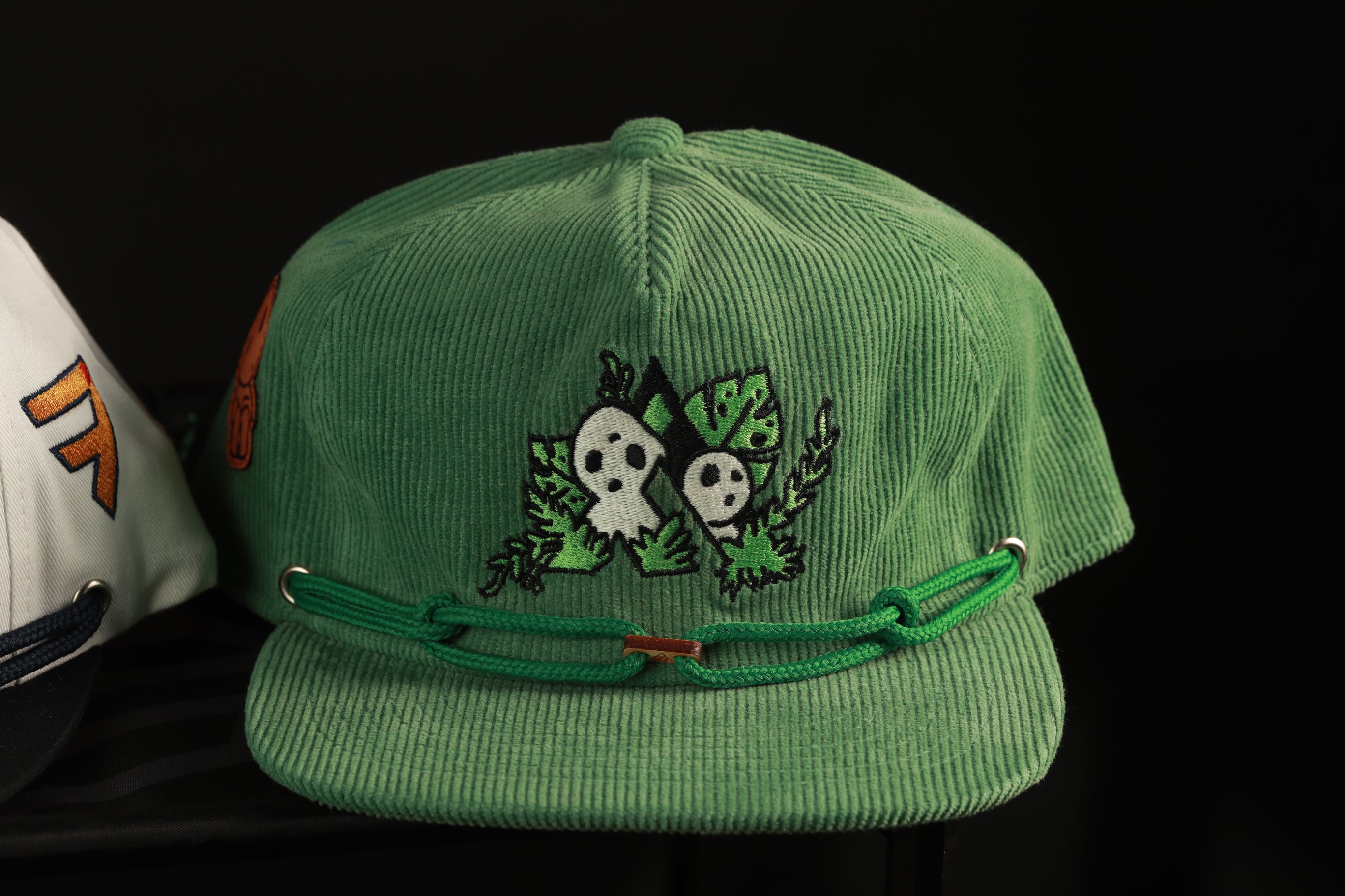 A green baseball cap with a unique embroidered design on the front.