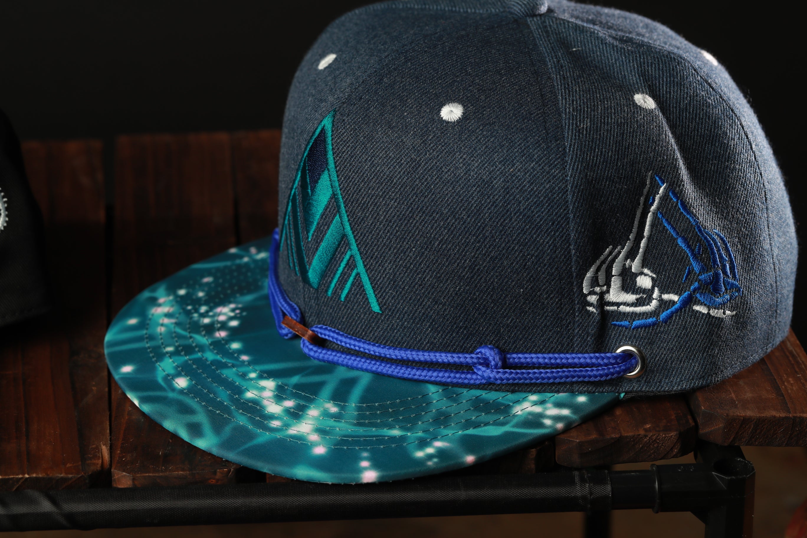A dark blue baseball cap with a teal pattern and white polka dots, resting on a wooden surface.