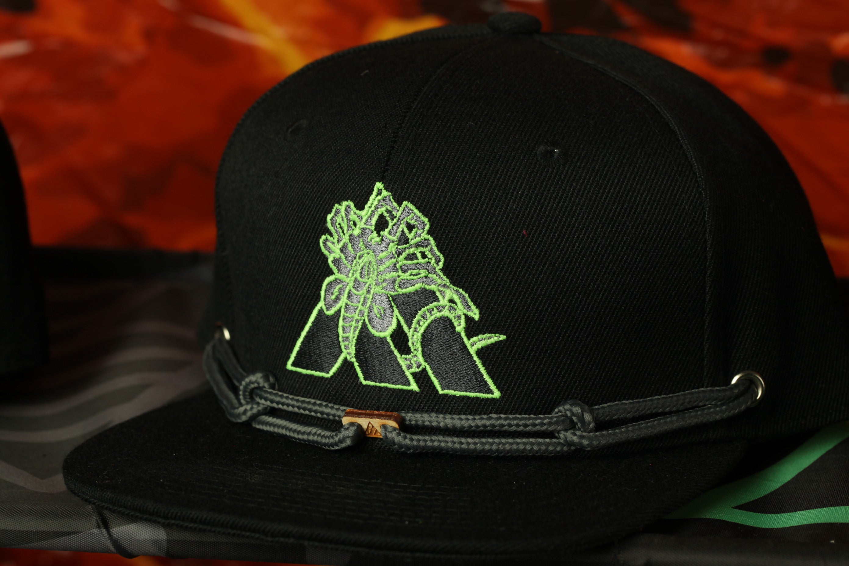 A black baseball cap with a green and black graphic design on the front.
