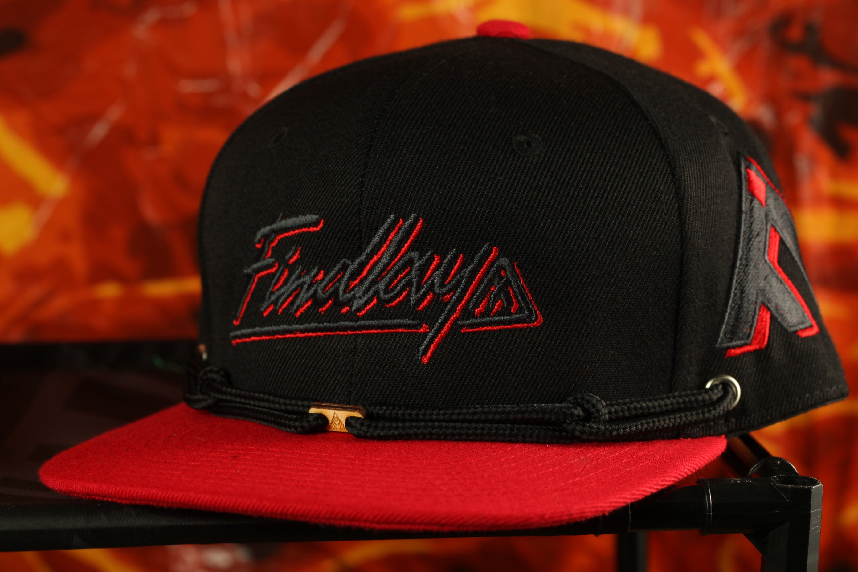 A black baseball cap with red detailing, featuring the word "FineByzies" embroidered on it.