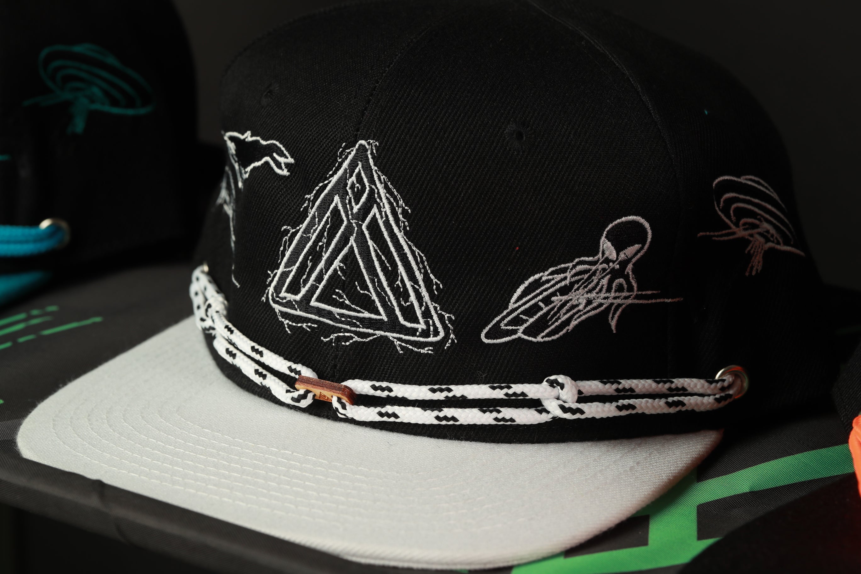 A black baseball cap with white embroidered designs on the front.