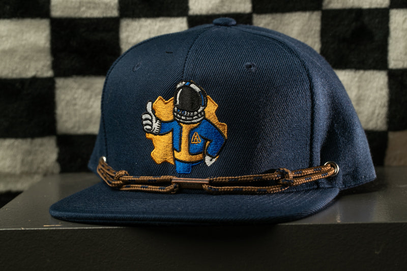 A navy blue baseball cap with a graphic of a person wearing a blue and yellow outfit, giving the impression of a character from a video game.