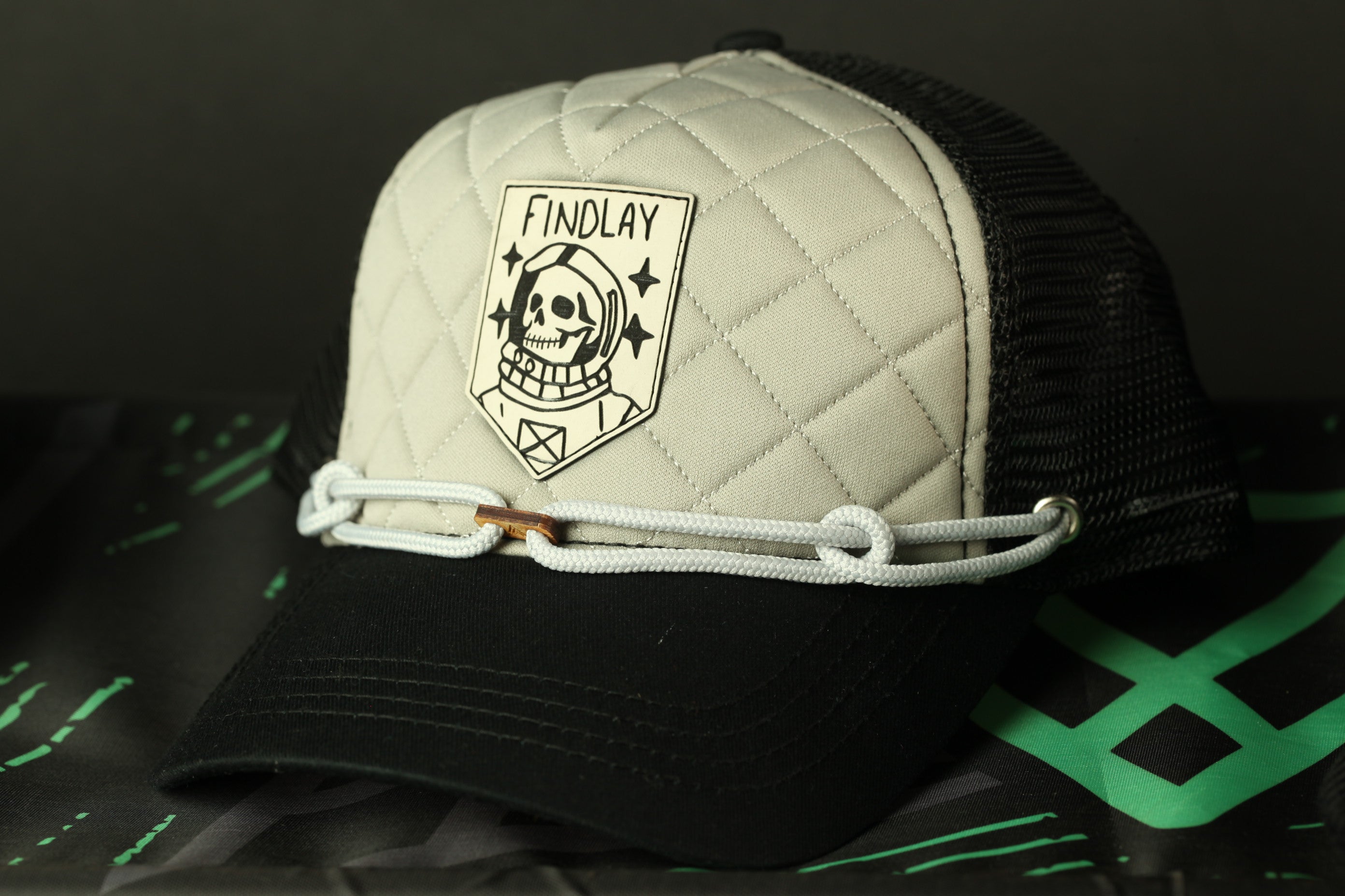 A black and white baseball cap with a quilted pattern and a skull and crossbones design on the front.