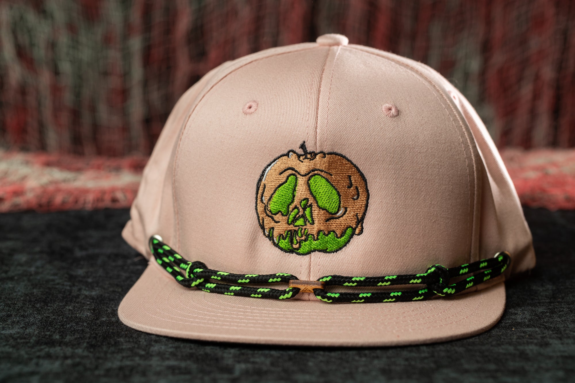 A pink baseball cap with a green skull design on the front.