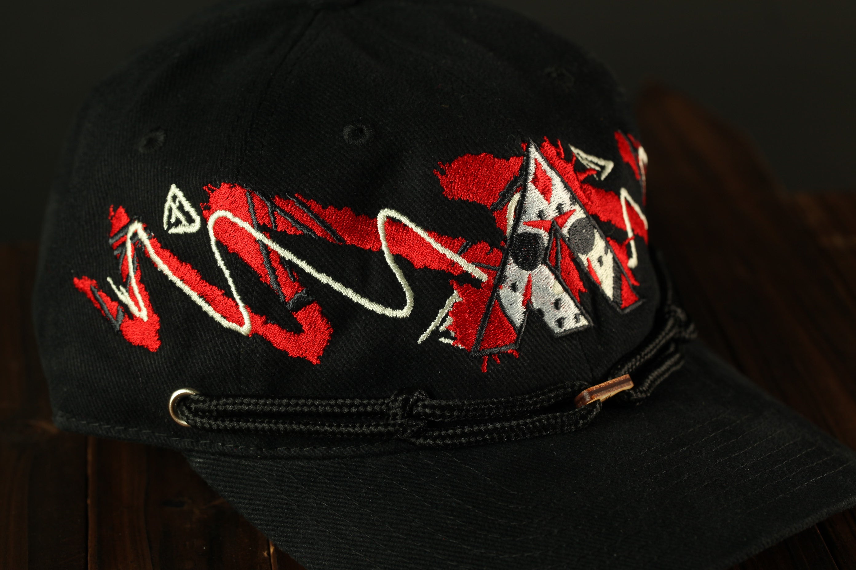 A black baseball cap with red and white embroidered designs on the front.