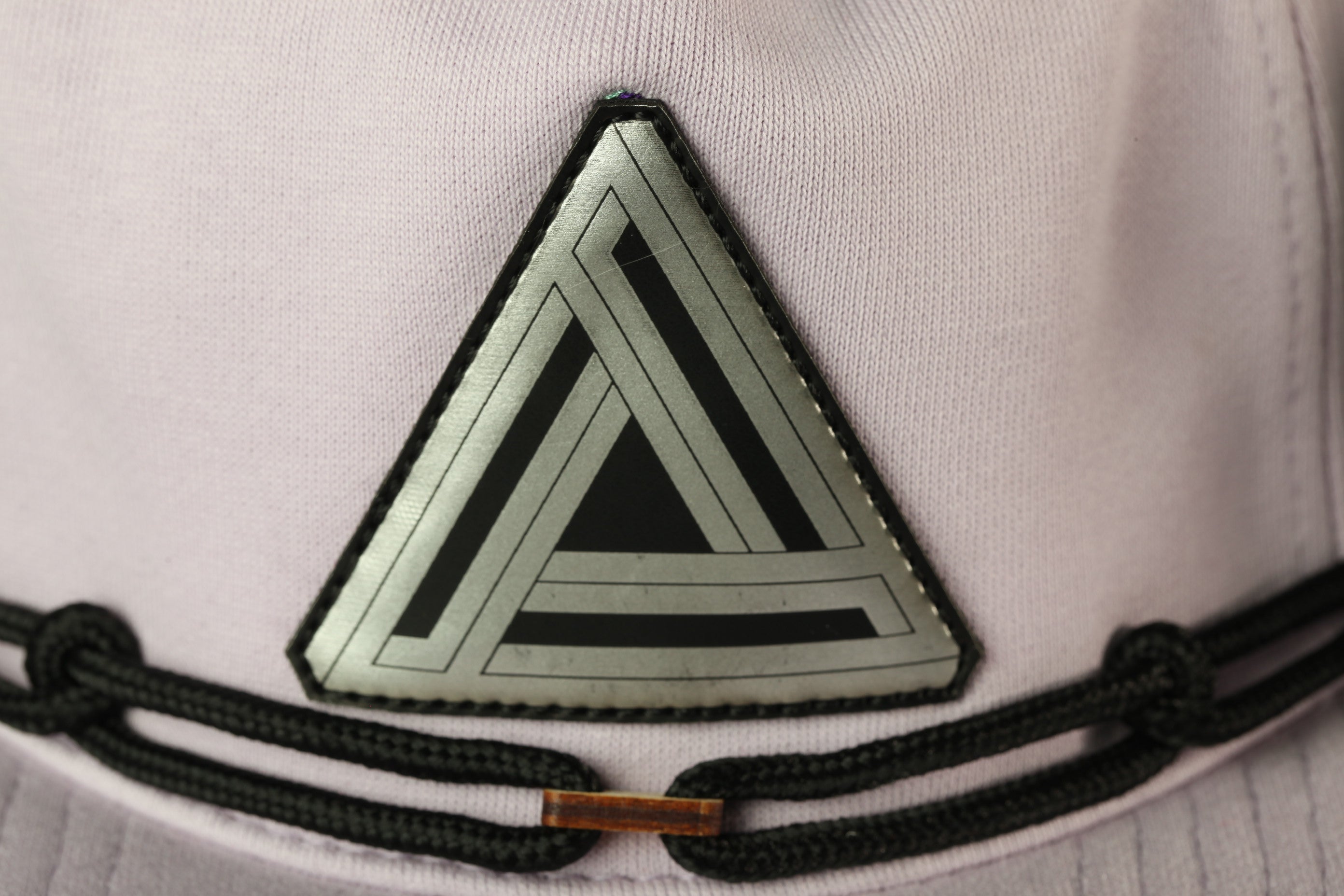 A close-up view of a triangular patch with a geometric pattern on a fabric surface, possibly a hat or garment.