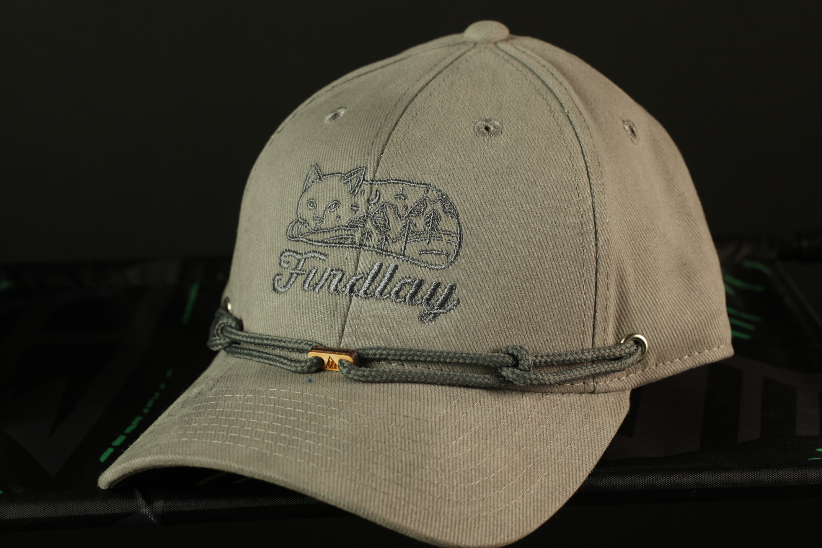A gray baseball cap with a cat design and the word "Findlay" printed on it.