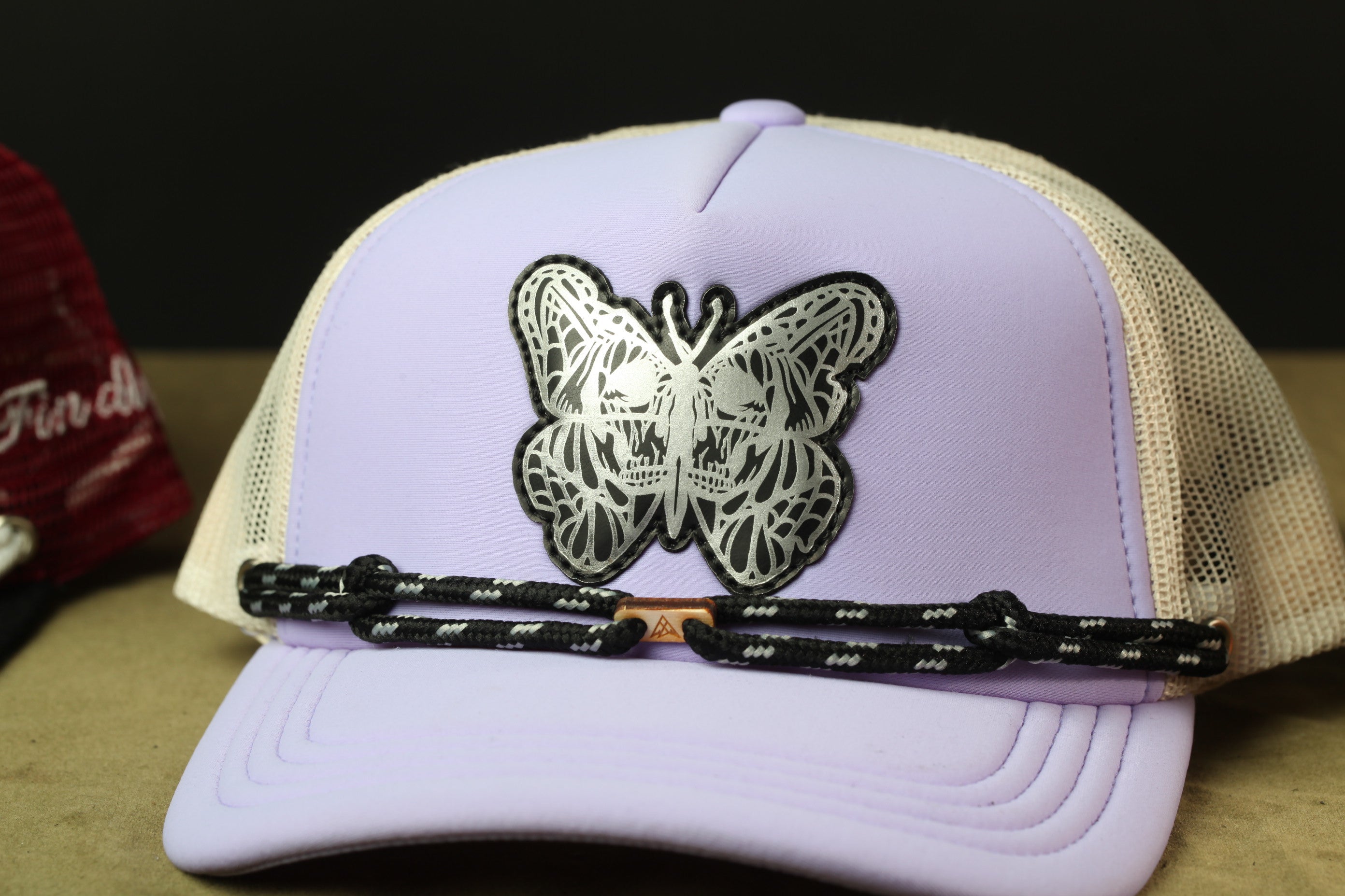 A purple baseball cap with a butterfly design on the front.