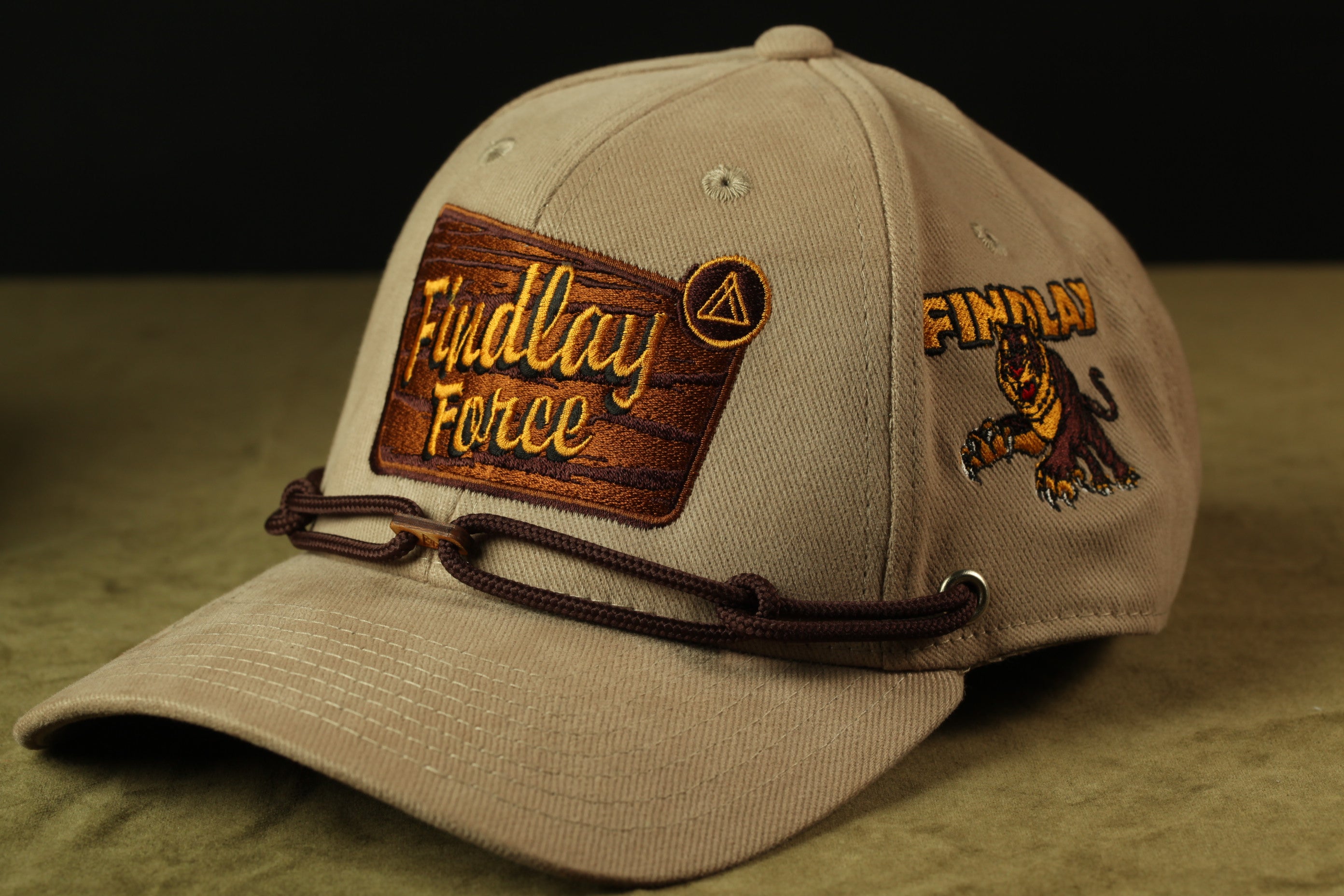 A tan baseball cap with a wooden patch and a logo, featuring the text "Fluidlay Force" and a graphic of a tiger.