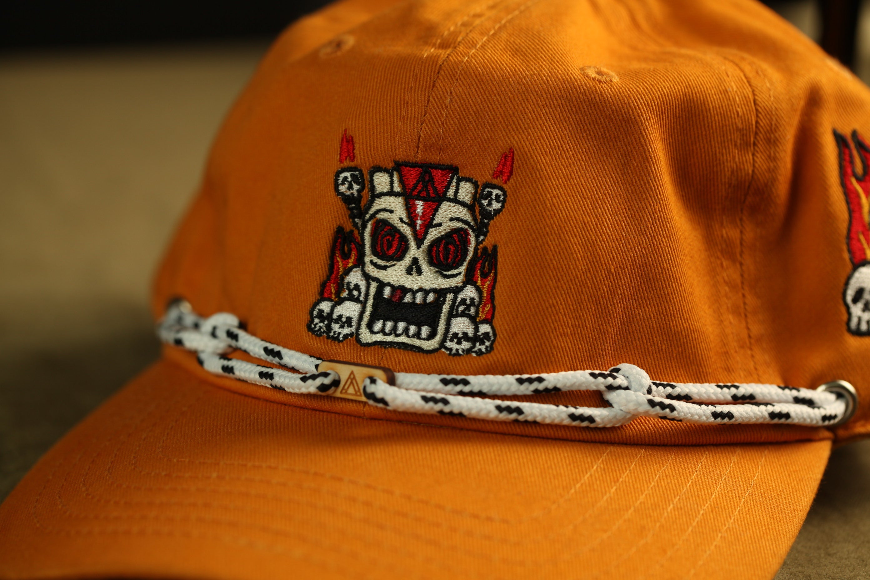 An orange baseball cap with a skull and crossbones design on the front.
