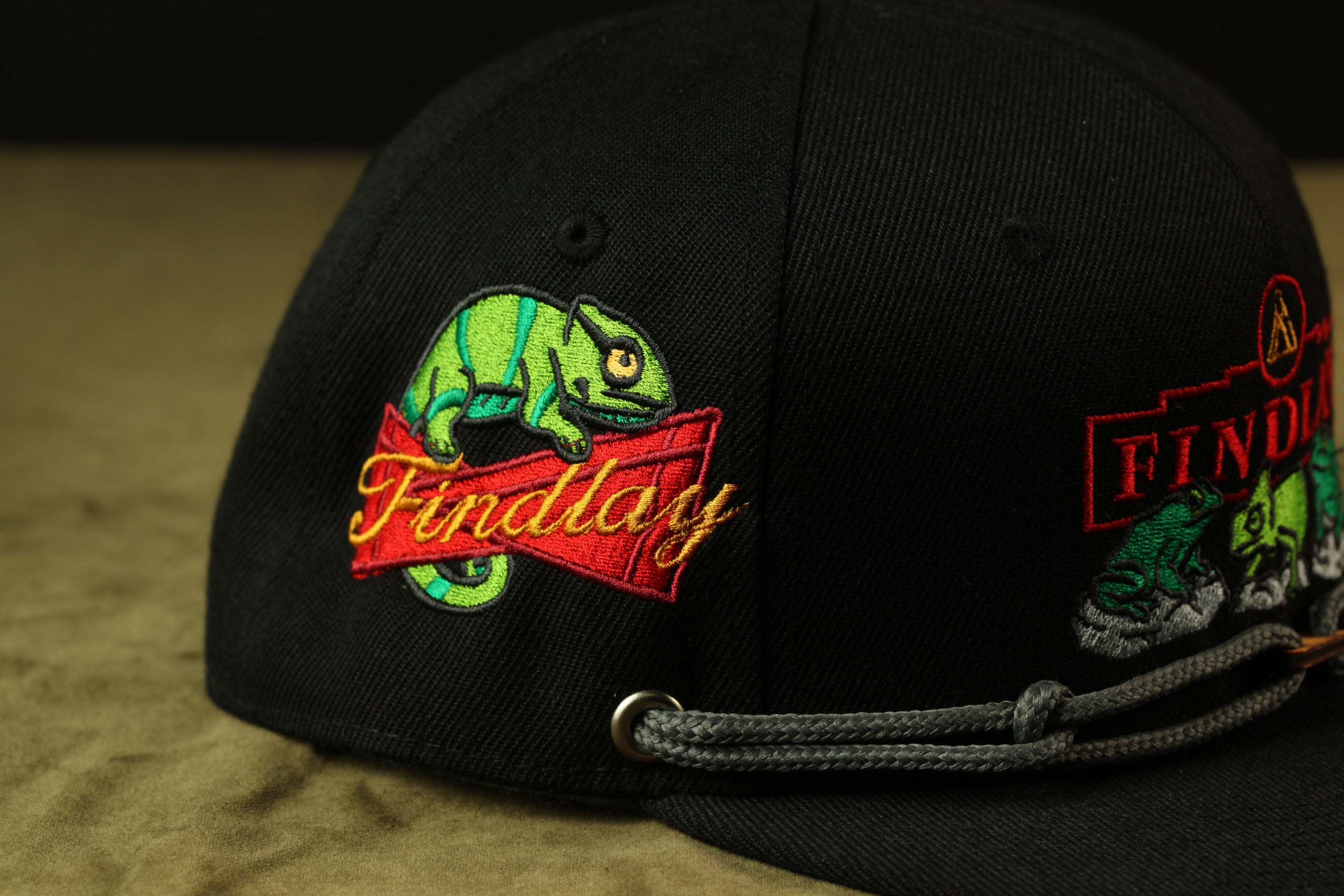 A close-up view of a black baseball cap with a colorful embroidered design on the front.