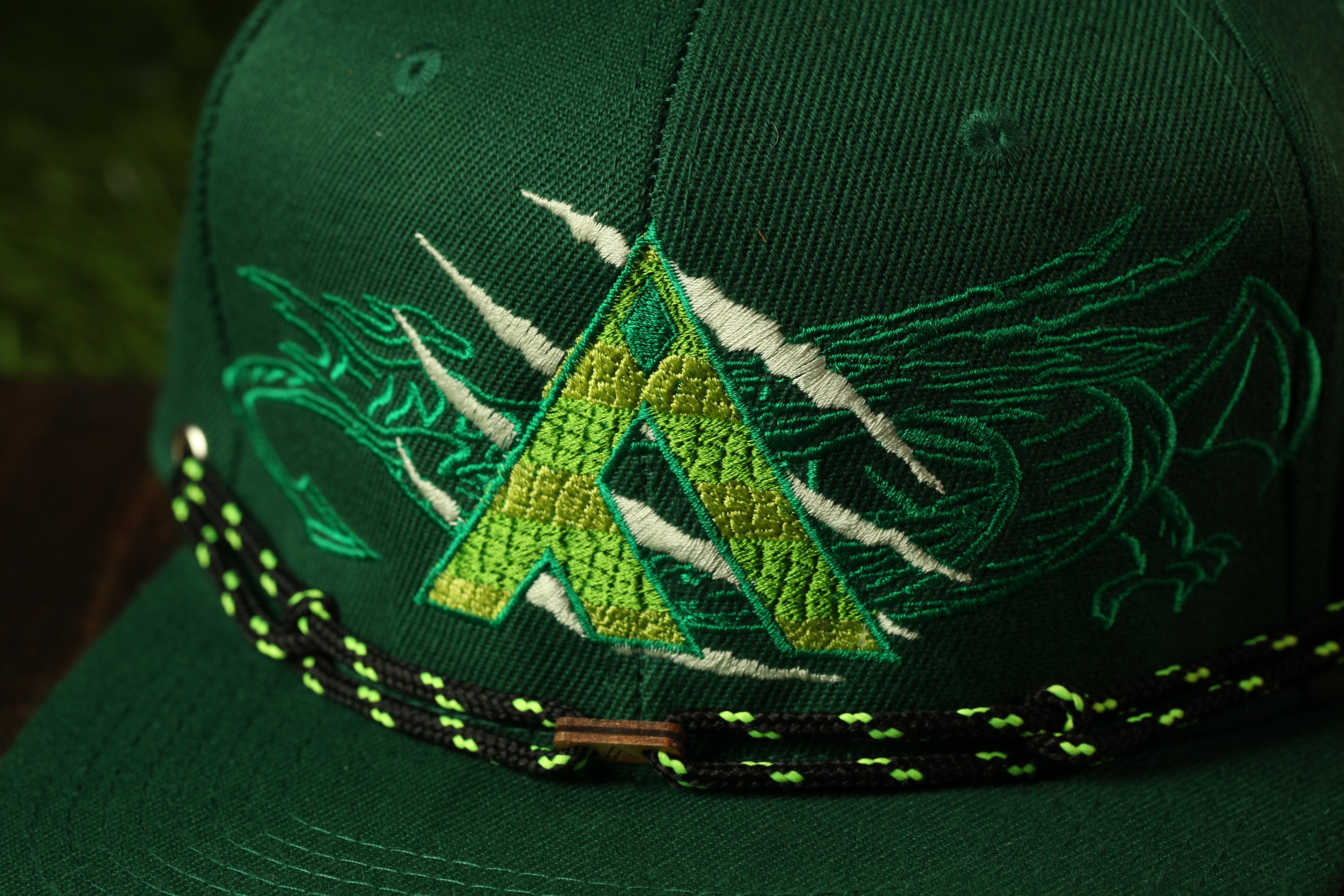 A close-up view of a green baseball cap with a dragon design on it.