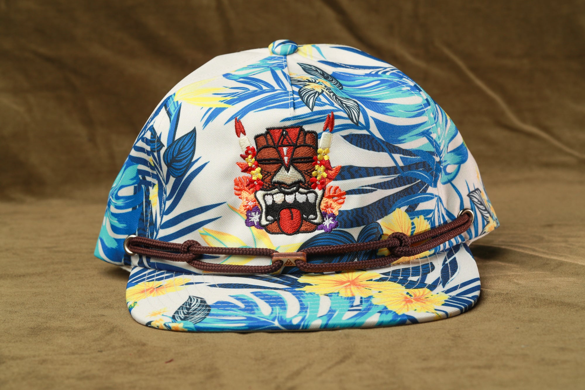 A colorful tropical-themed baseball cap with a tiki mask design and floral patterns.