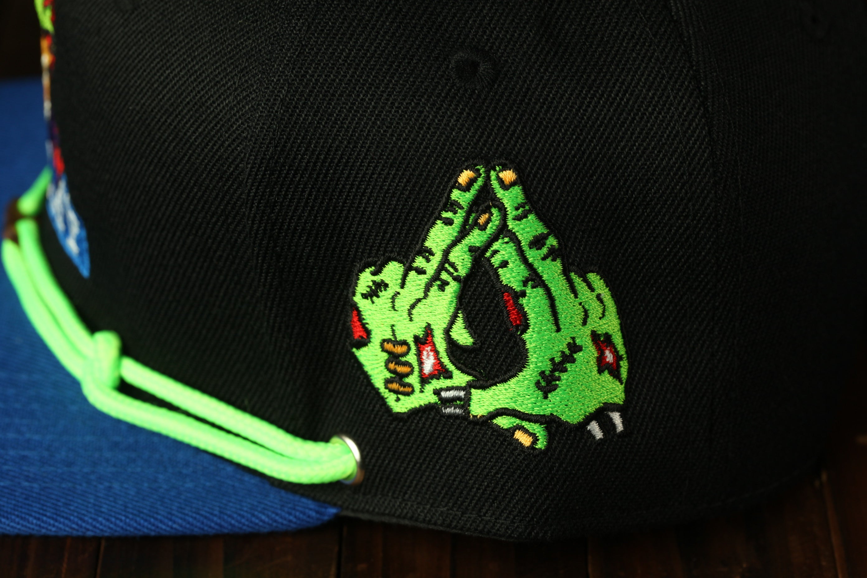 a close-up view of a black baseball cap with a green and black embroidered design on the front.