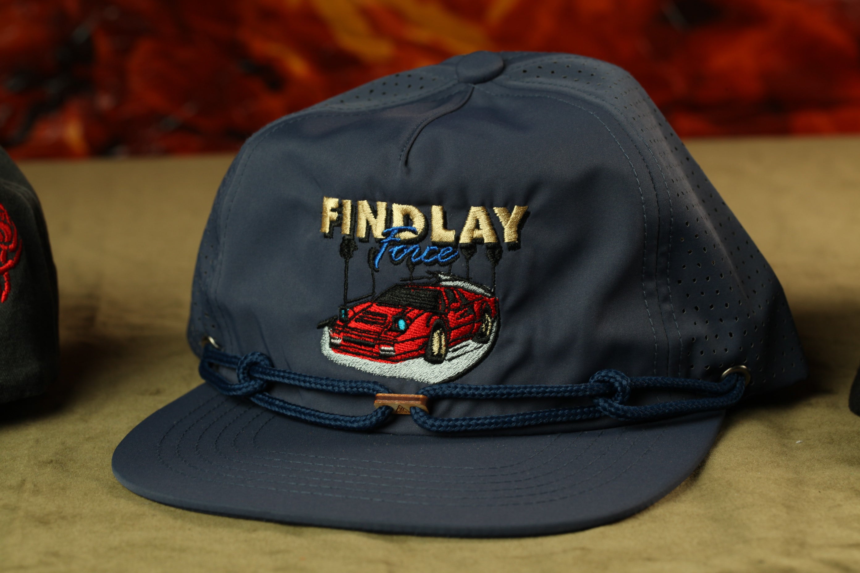 A navy blue baseball cap with a red car embroidered on it, featuring the text "FINDlay Force" on the front.