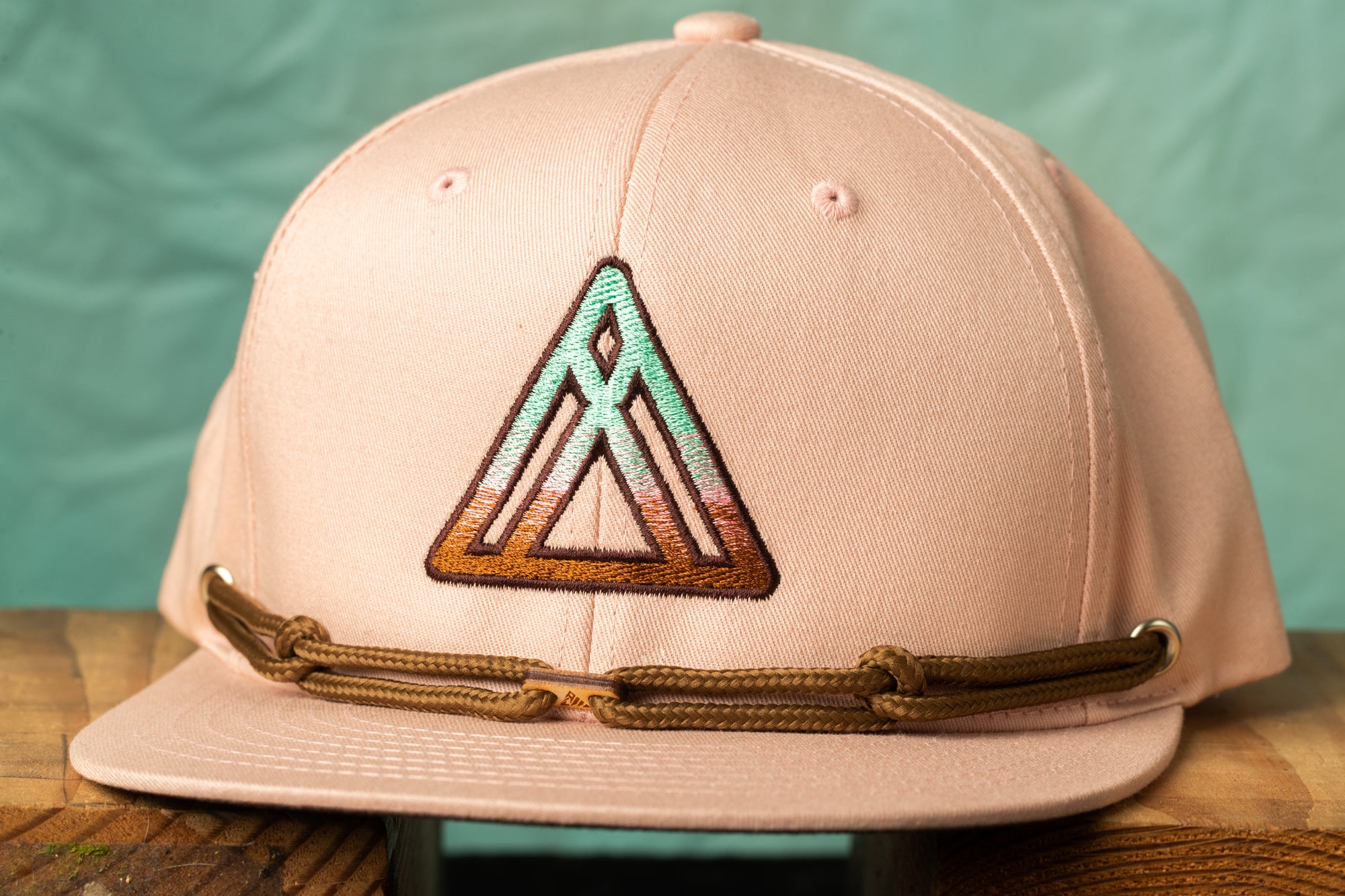 A pink baseball cap with a geometric pattern on the front.