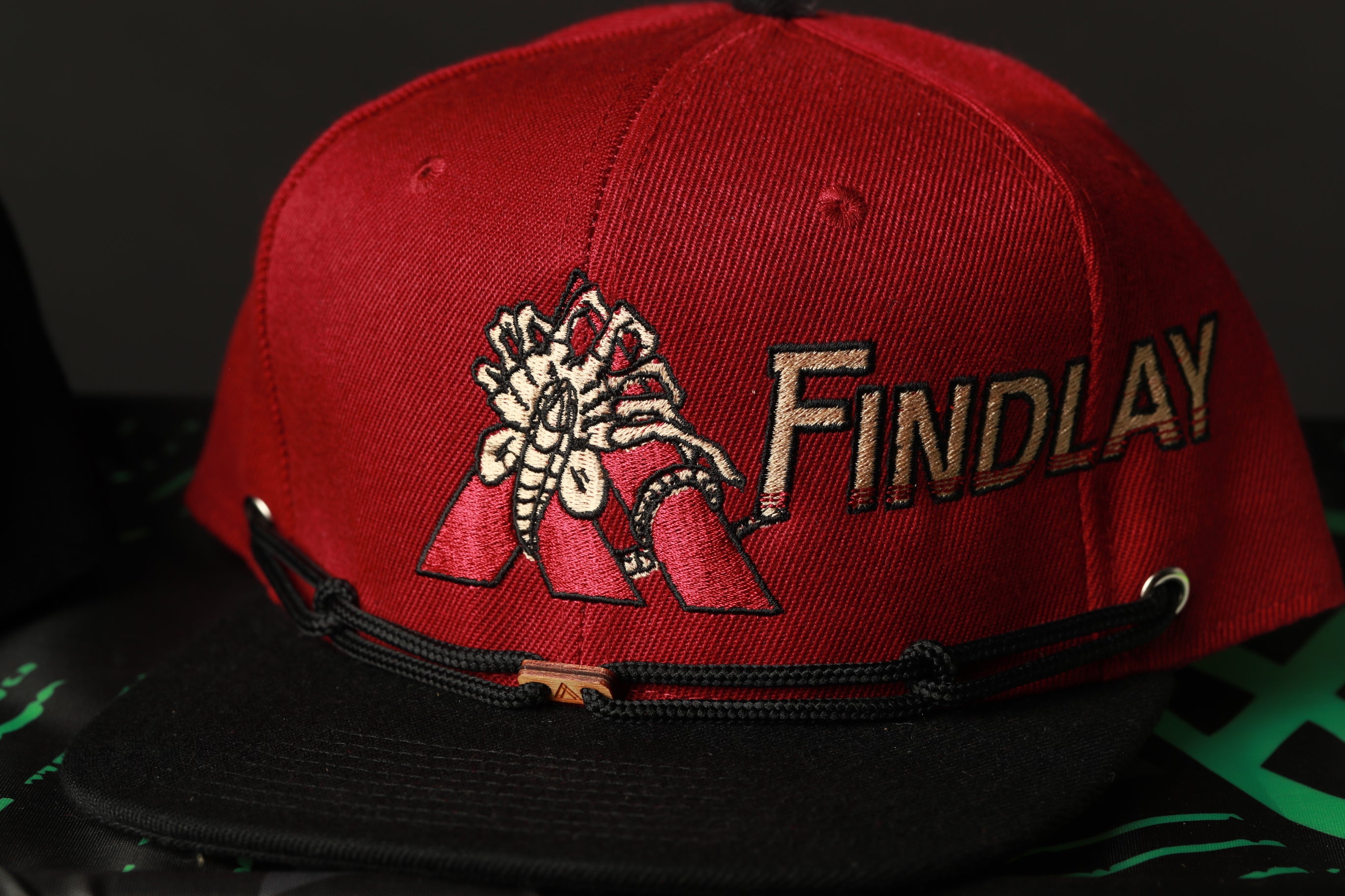 A red baseball cap with a black brim and a black strap.