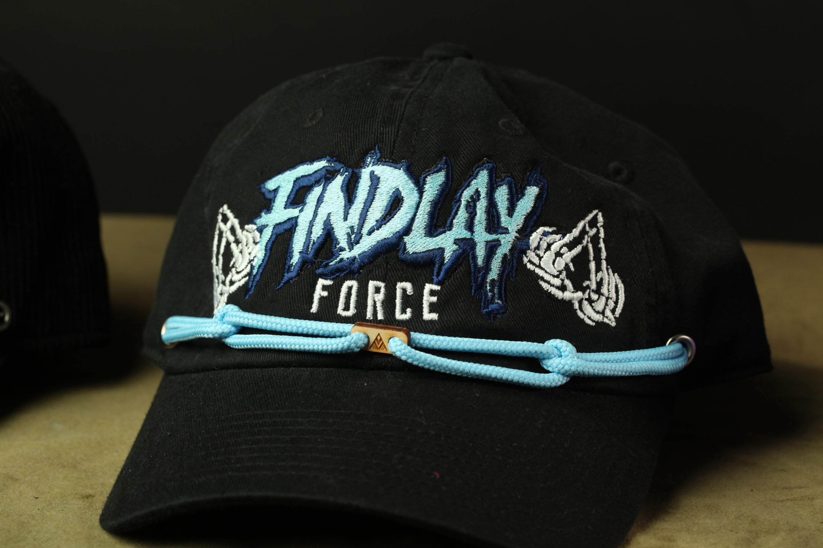 A black baseball cap with blue and white text and graphics on it.