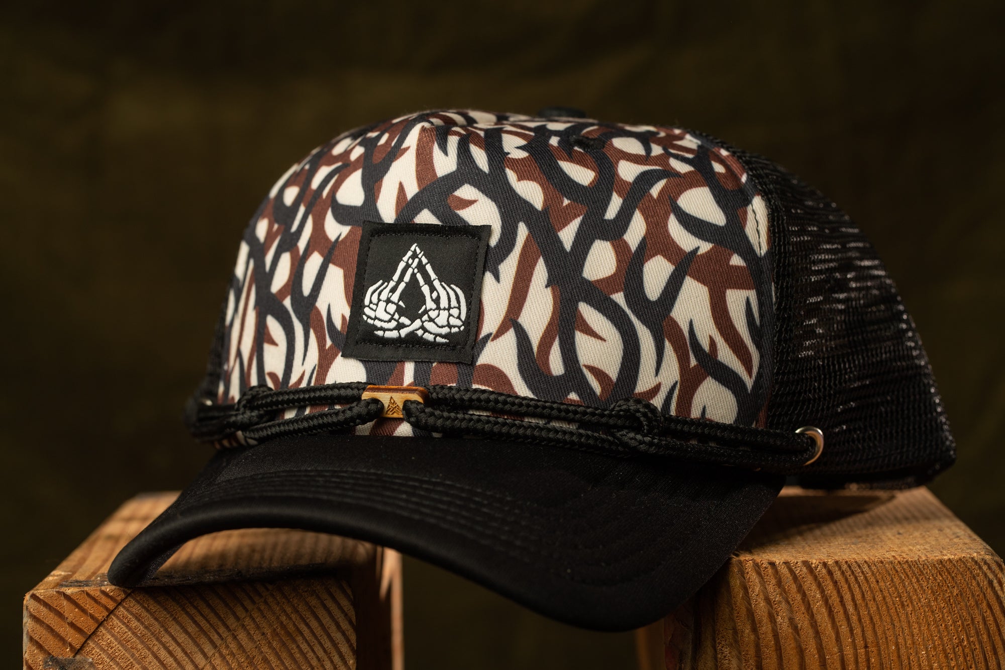 A black and white patterned baseball cap with a black band and a white logo on the front, resting on a wooden surface.