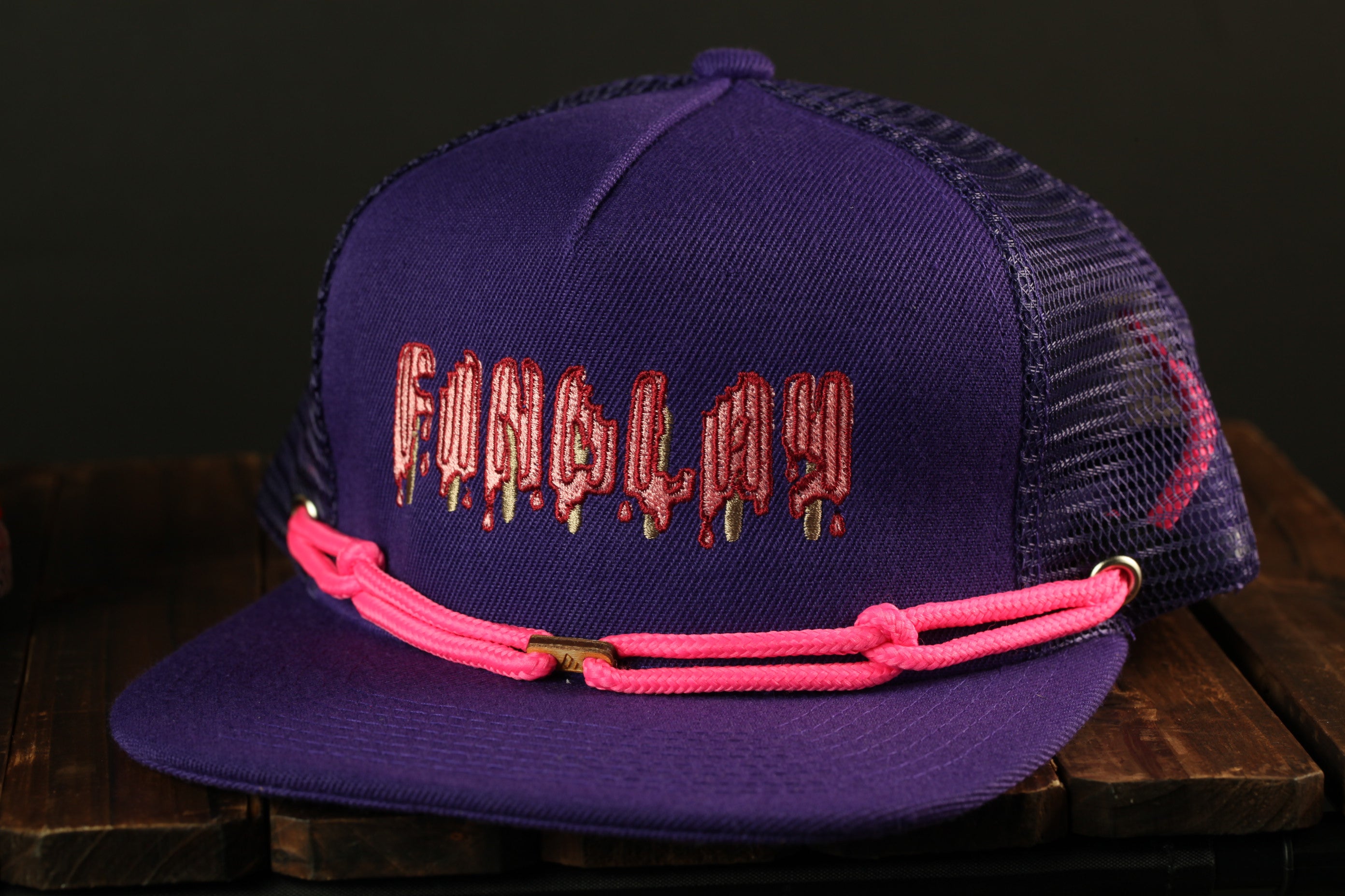 A purple baseball cap with a pink strap and the word "FUBU" printed on it.