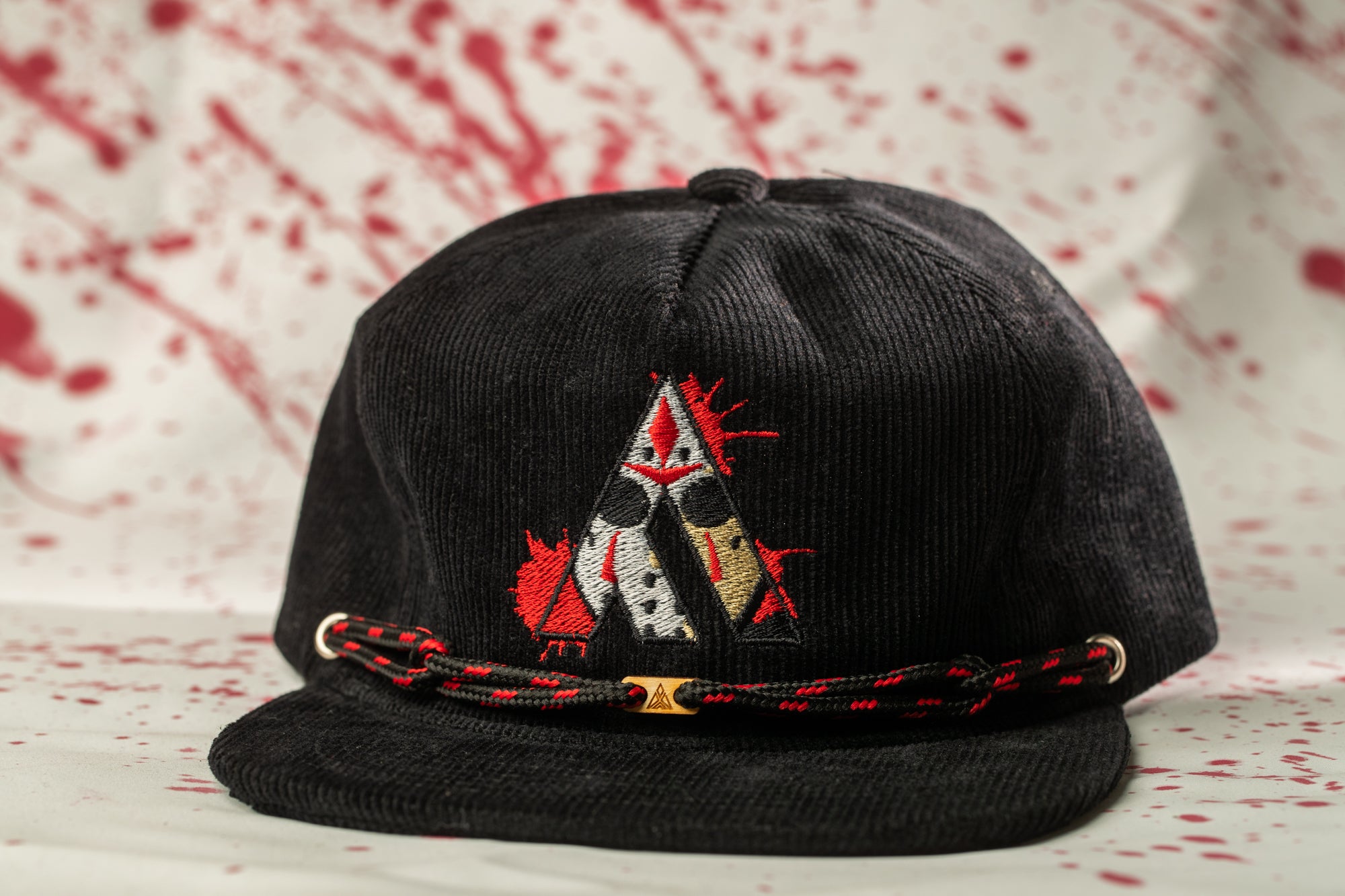 A black baseball cap with a red and white embroidered design on the front, featuring a stylized figure with a spiked hairstyle.