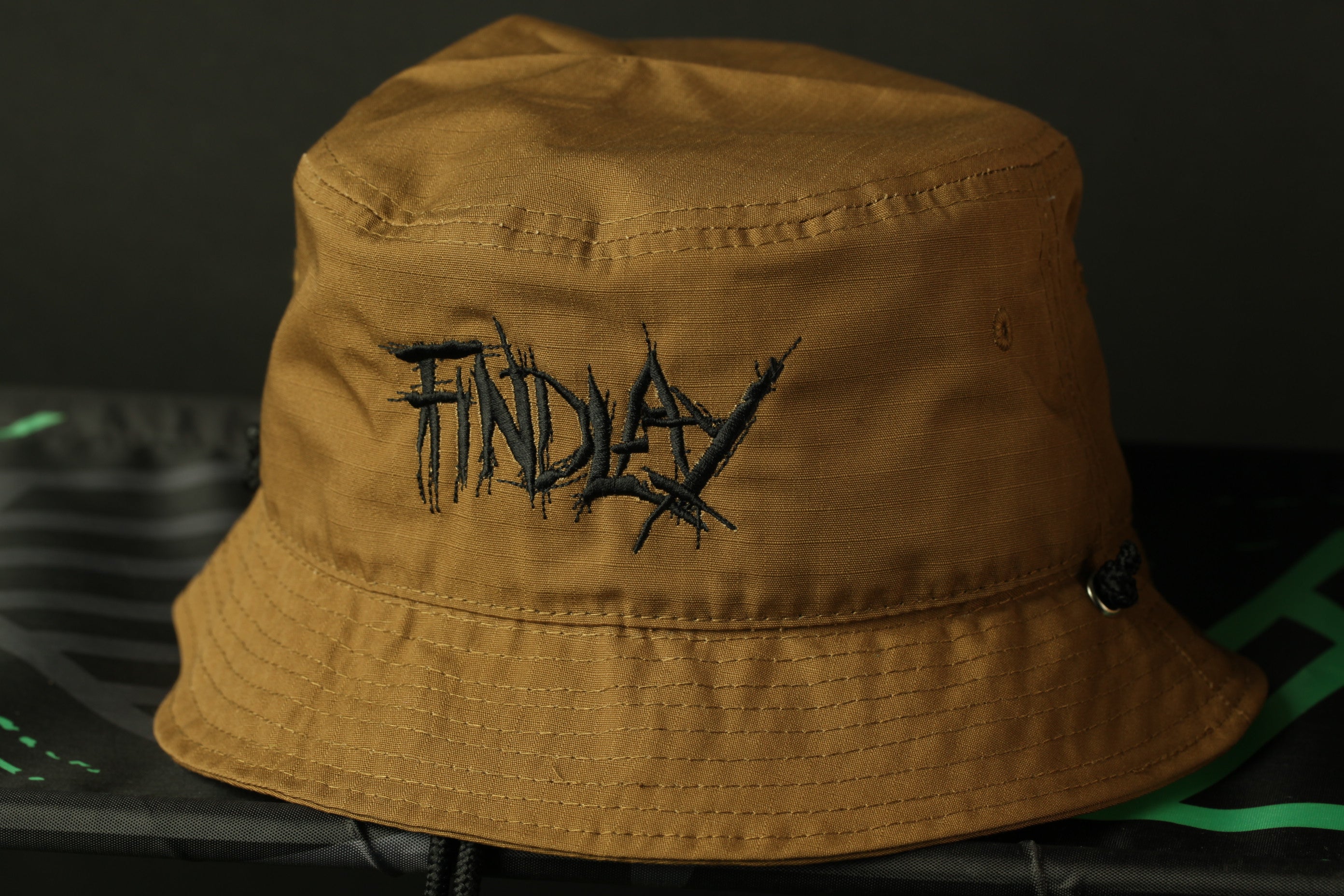 A brown bucket hat with the word "FINDAY" embroidered on it.