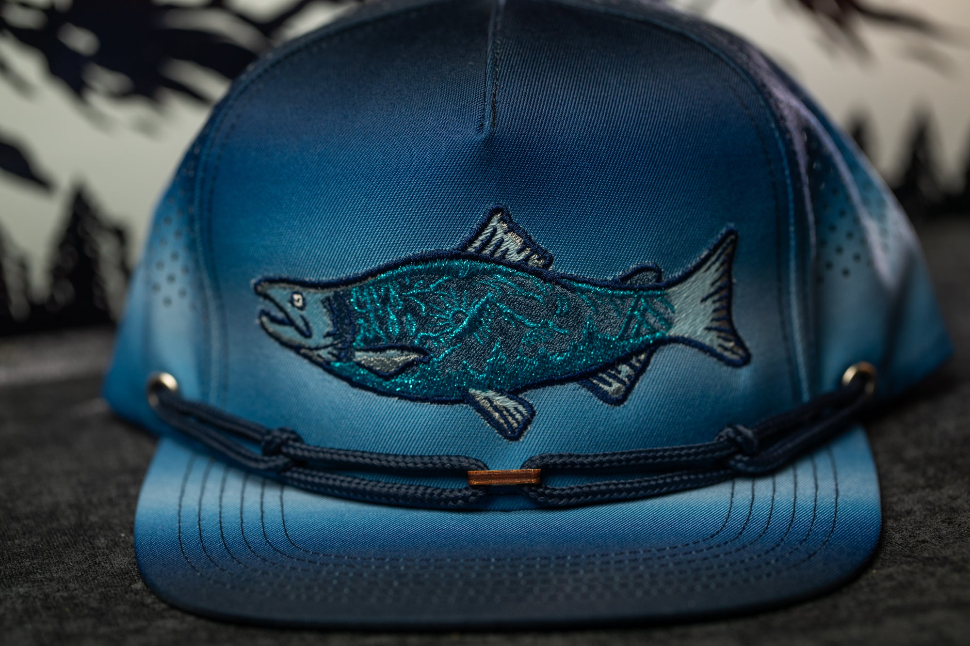 A blue baseball cap with a fish embroidered on it.