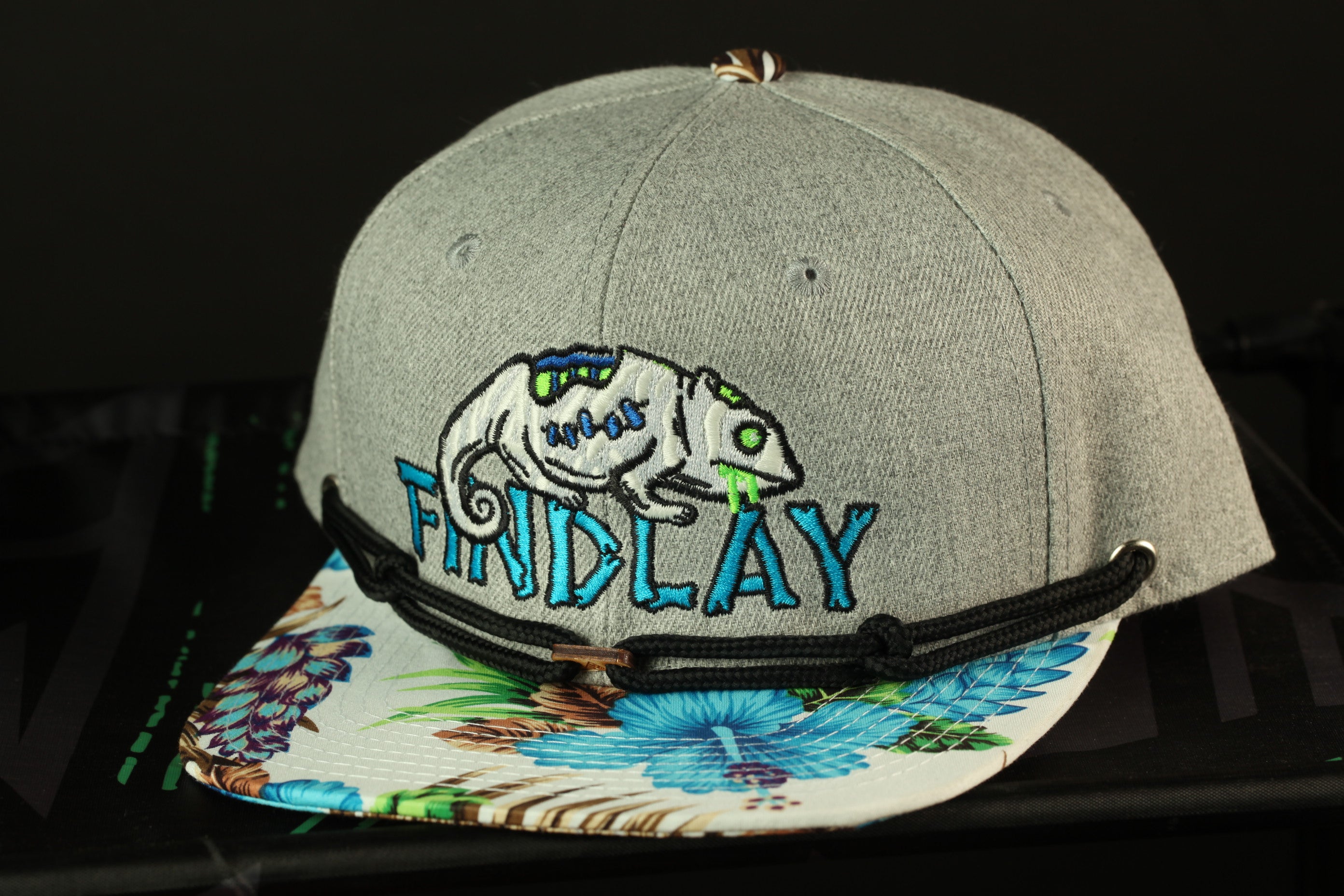 A gray baseball cap with a floral pattern and the word "FRIDAY" embroidered on it.