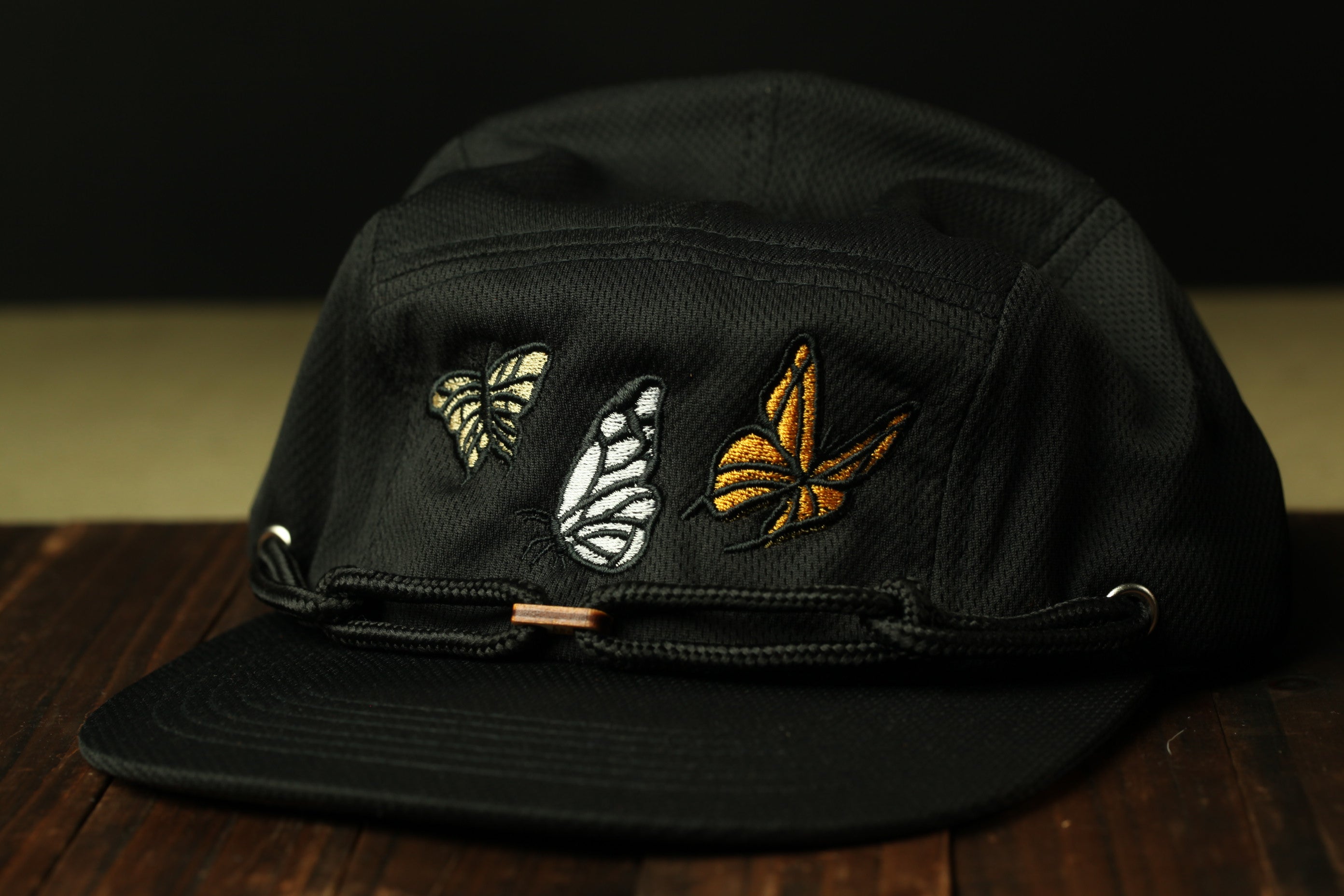 A black baseball cap with three embroidered butterflies on the front.