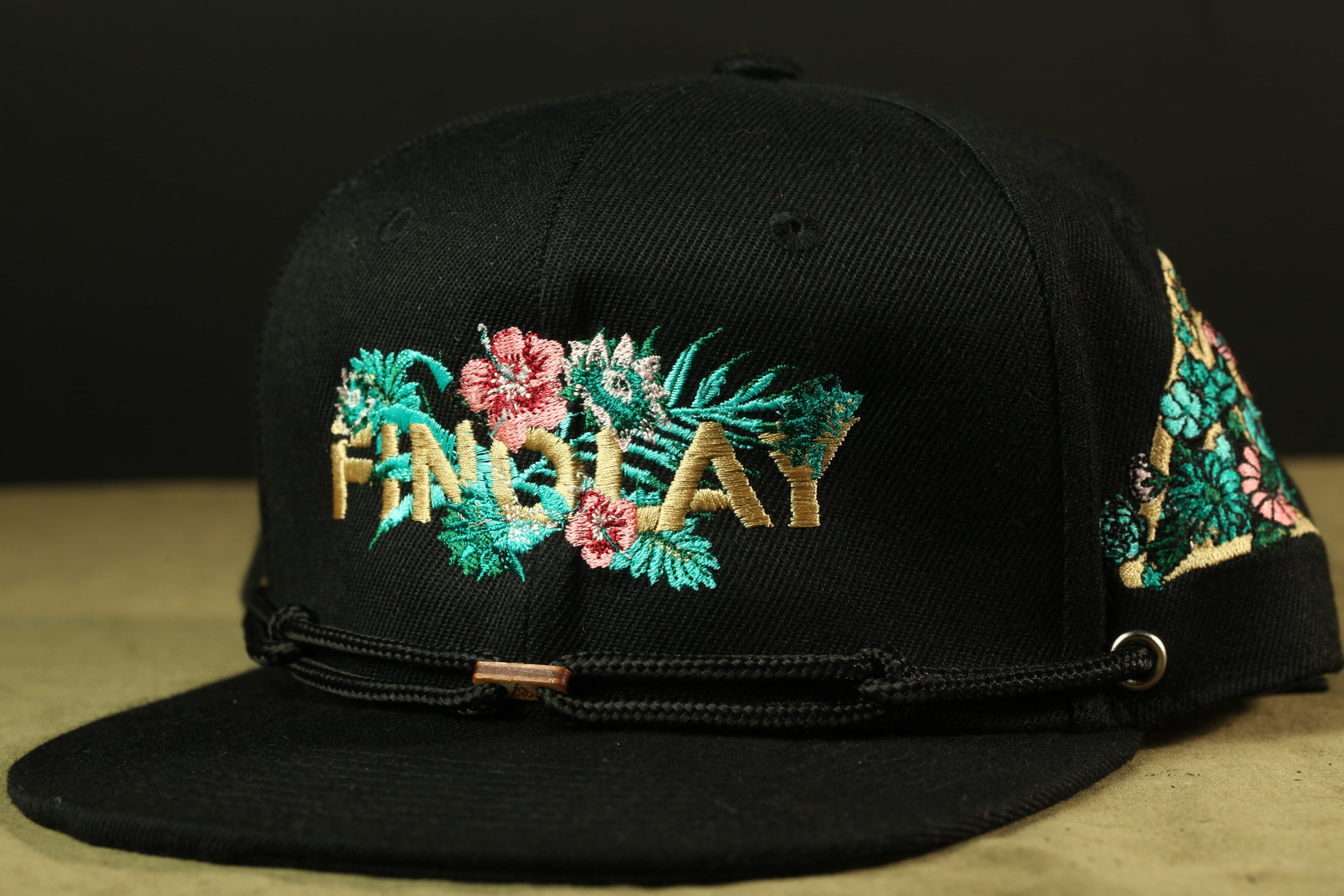 A black baseball cap with a floral embroidered design on the front.