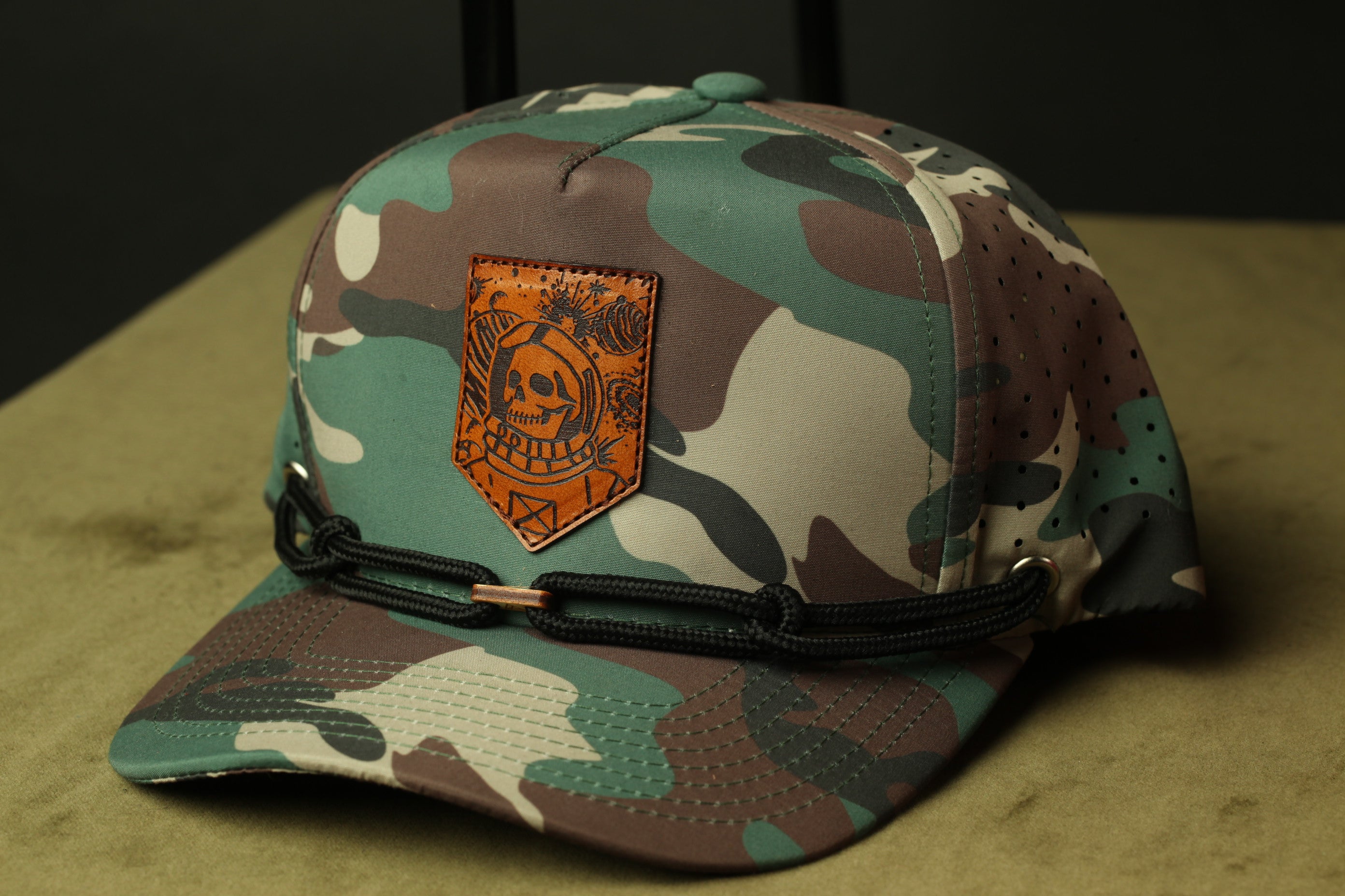 A camouflage baseball cap with a skull patch and a black strap.