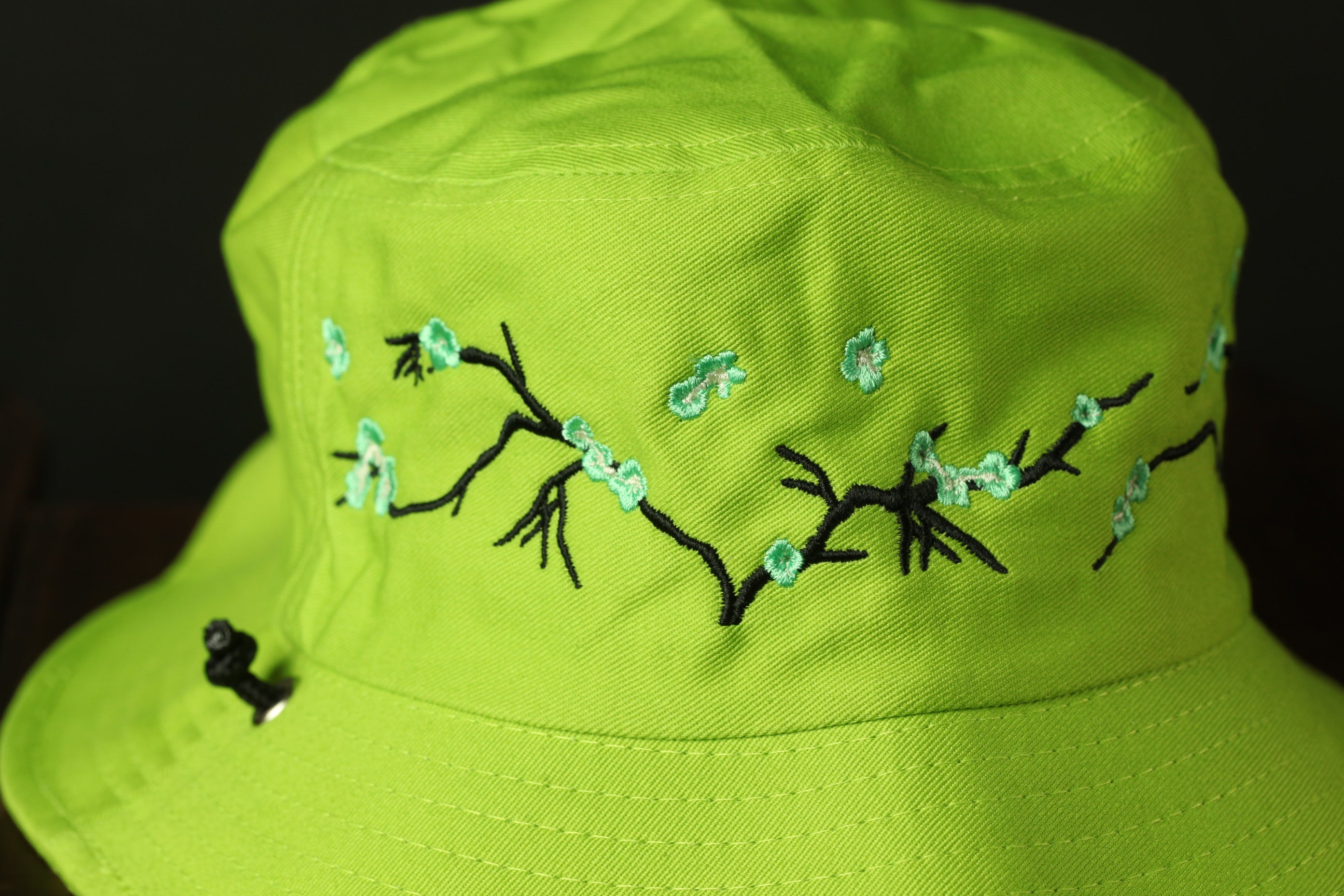 A bright green bucket hat with a floral embroidered pattern on the front.