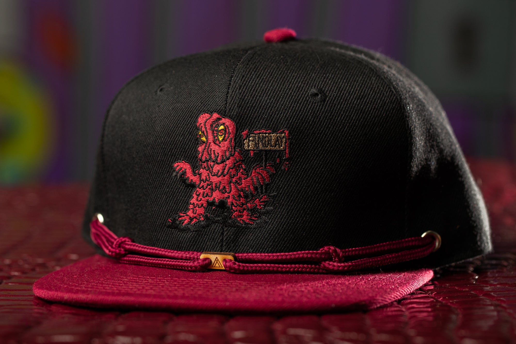 a black and red hat with a red dragon on it