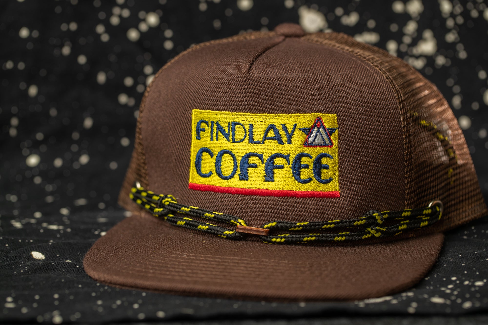 A brown baseball cap with a yellow and red logo that says "FINDLAY COFFEE".