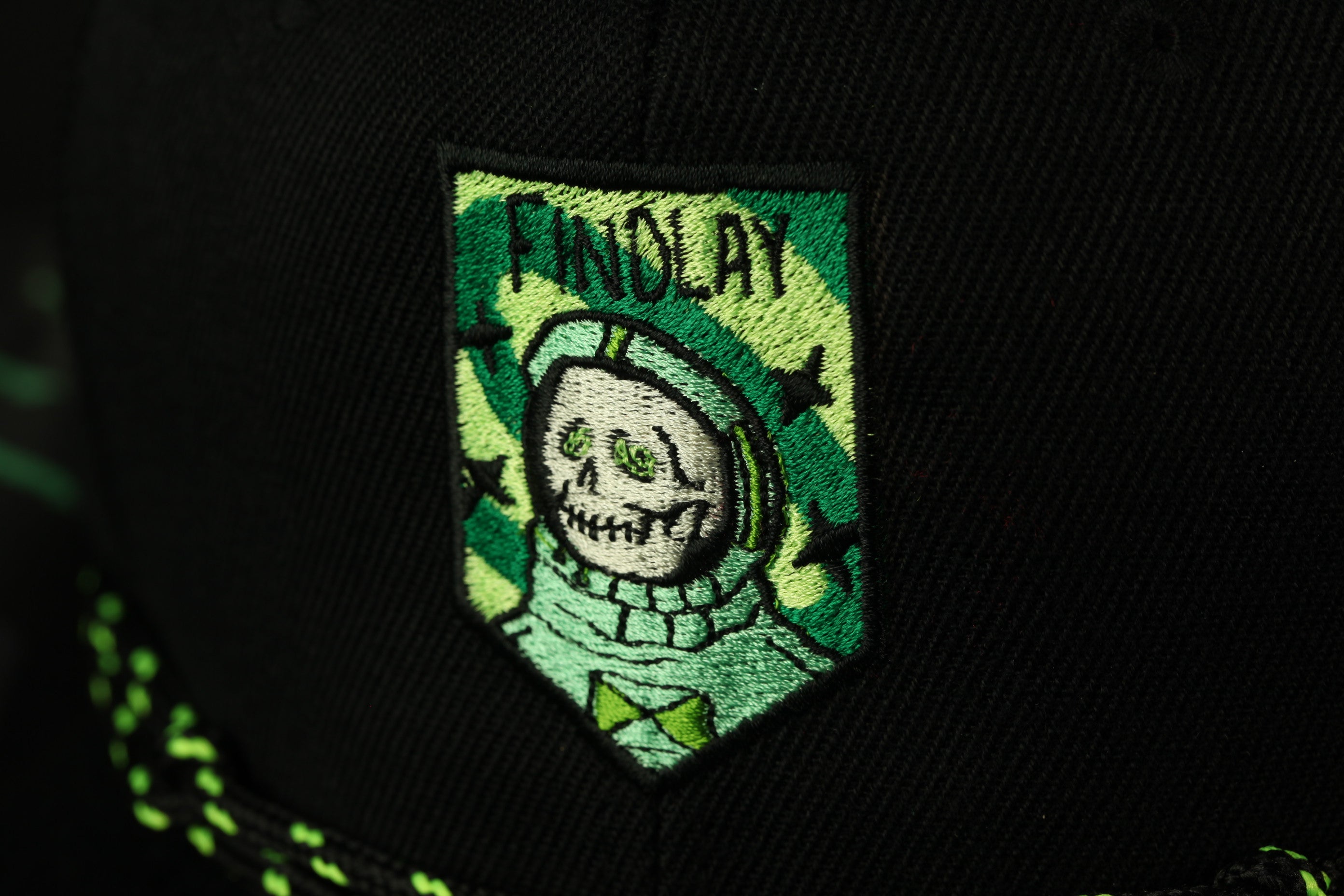 a close-up of a black baseball cap with a green and white embroidered patch on the front.