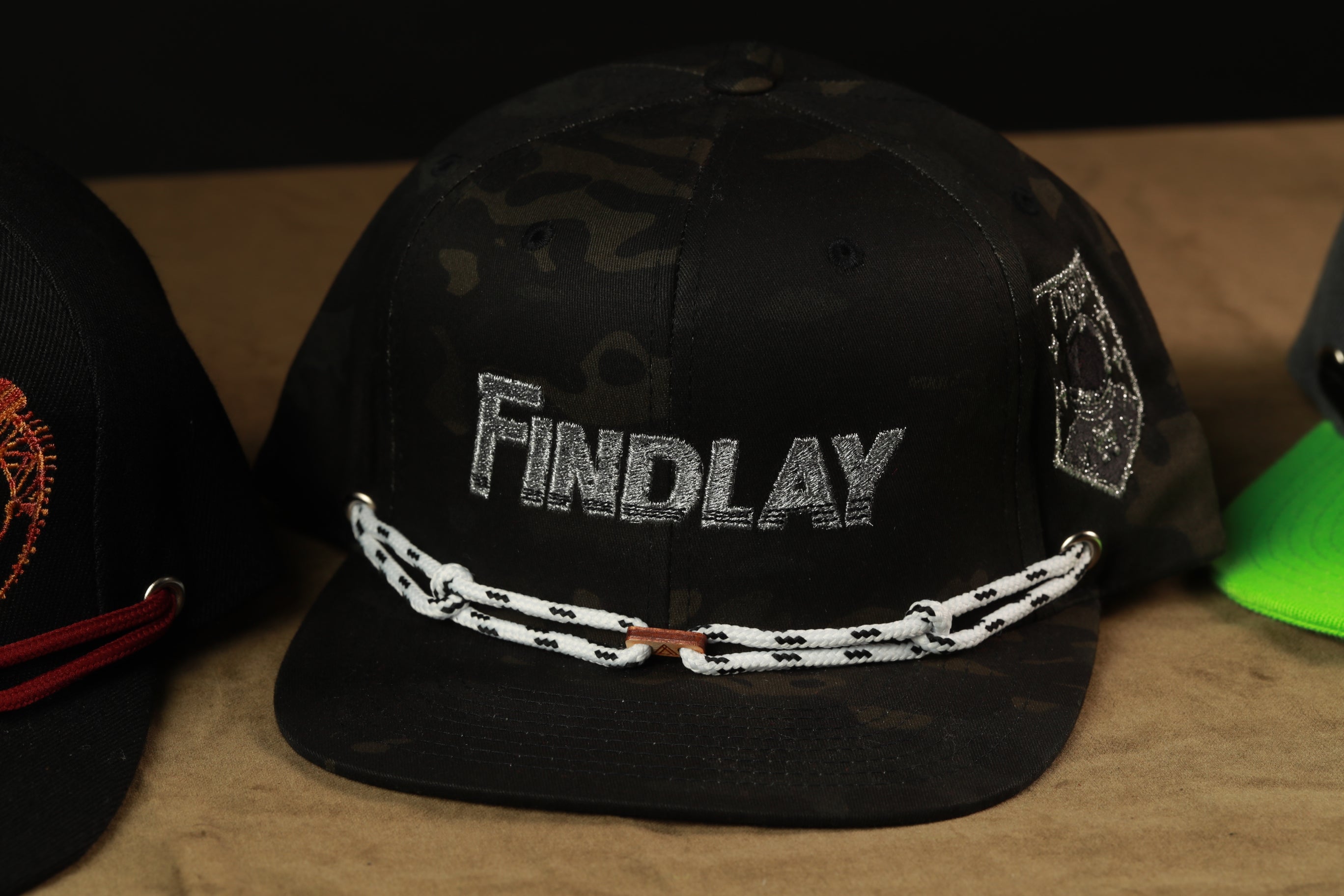 A black baseball cap with the word "Findlay" printed on it, along with a chain strap.
