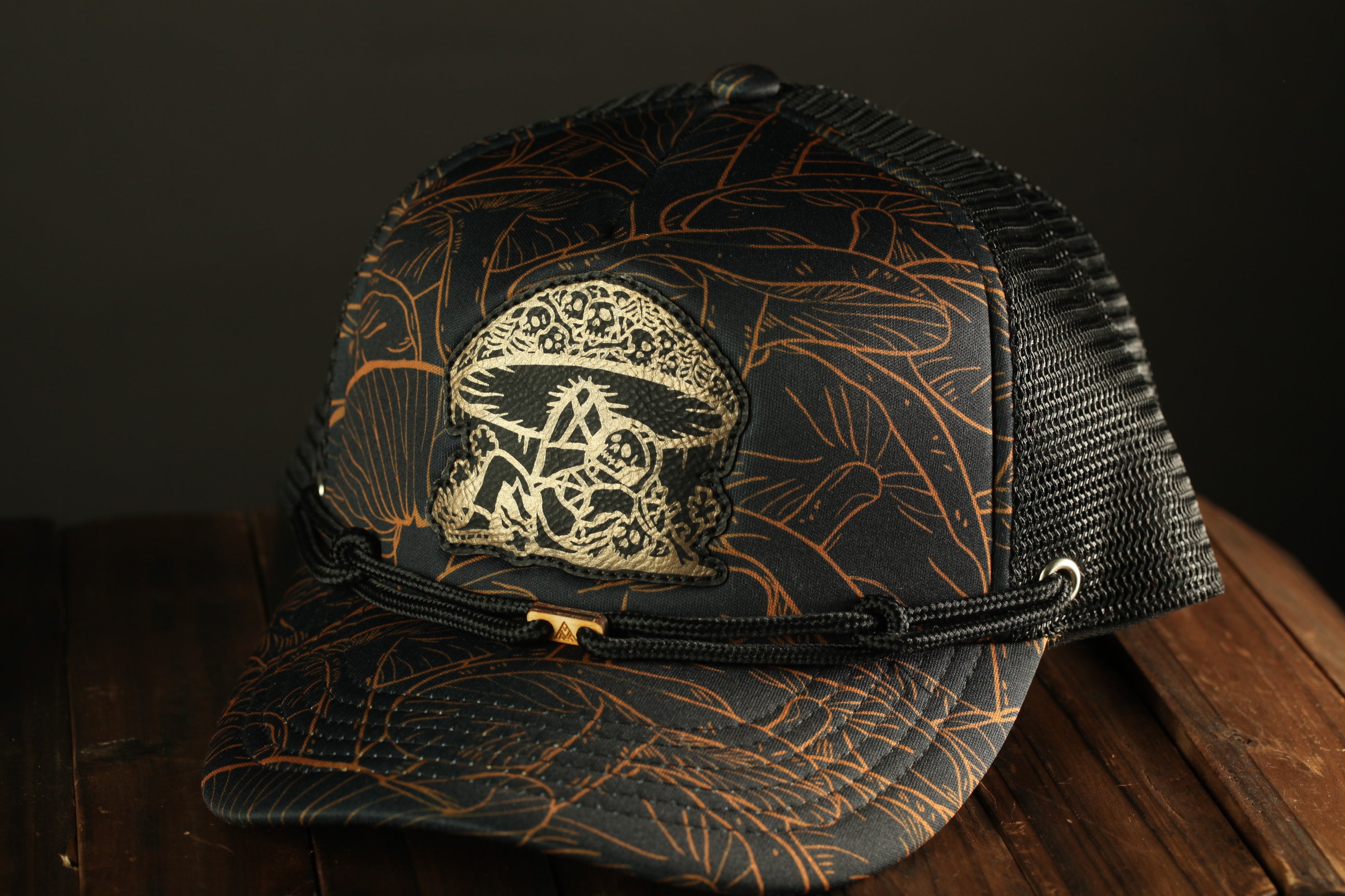 A black and gold patterned baseball cap with a unique mushroom-like design on the front.