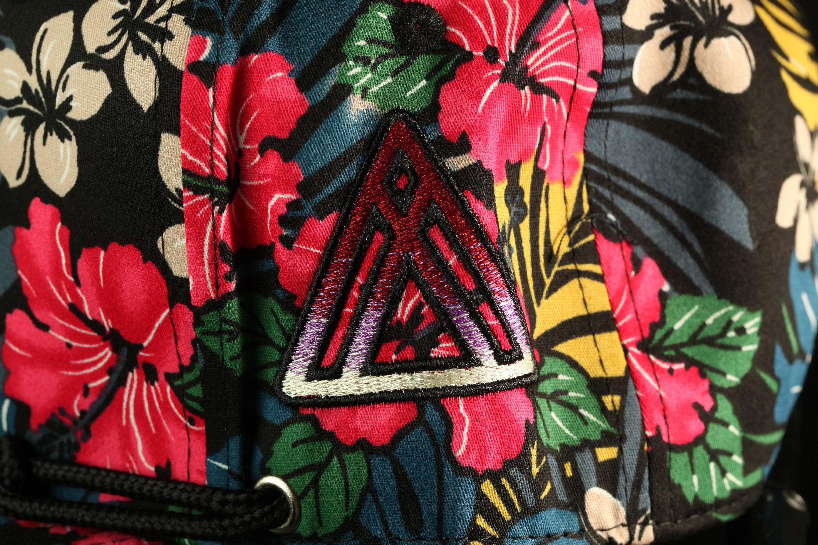 a close-up view of a colorful, floral-patterned fabric with a distinctive red triangle patch on it.