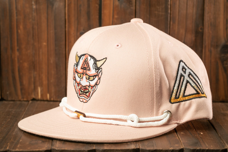 A pink baseball cap with a graphic design on the front, sitting on a wooden surface.