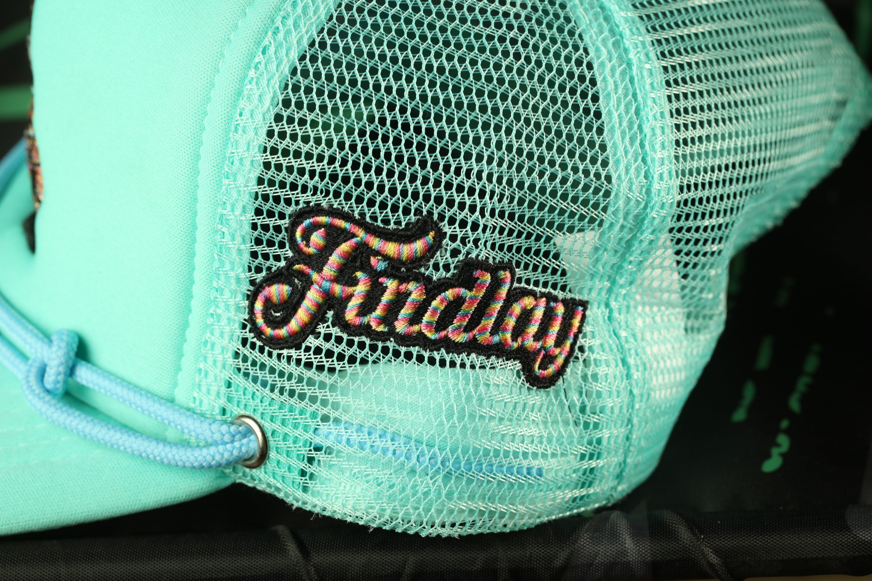 A turquoise baseball cap with a mesh back and a black logo on the front.