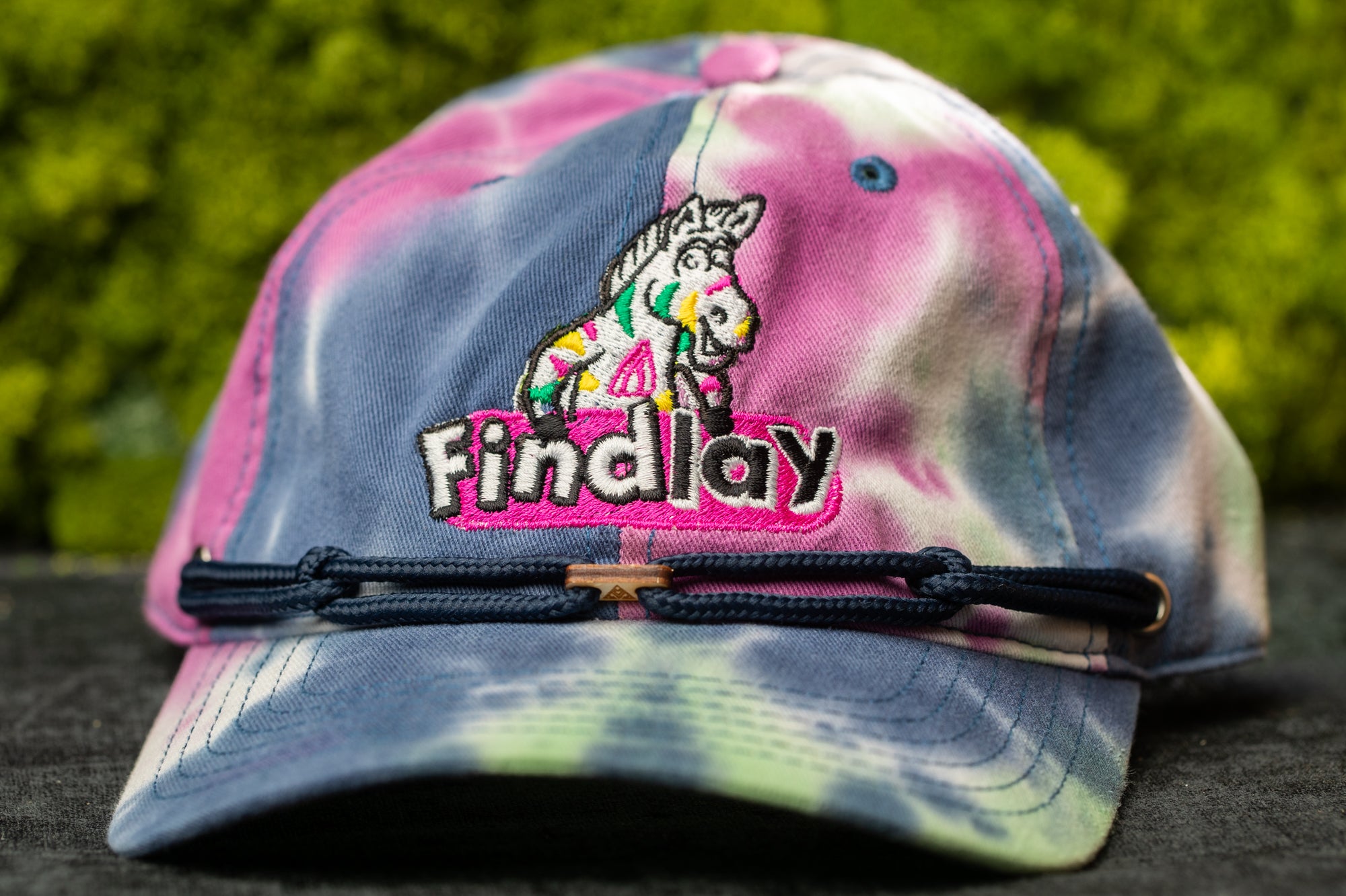 A tie-dye baseball cap with a cartoon zebra logo and the word "Findlay" printed on it.