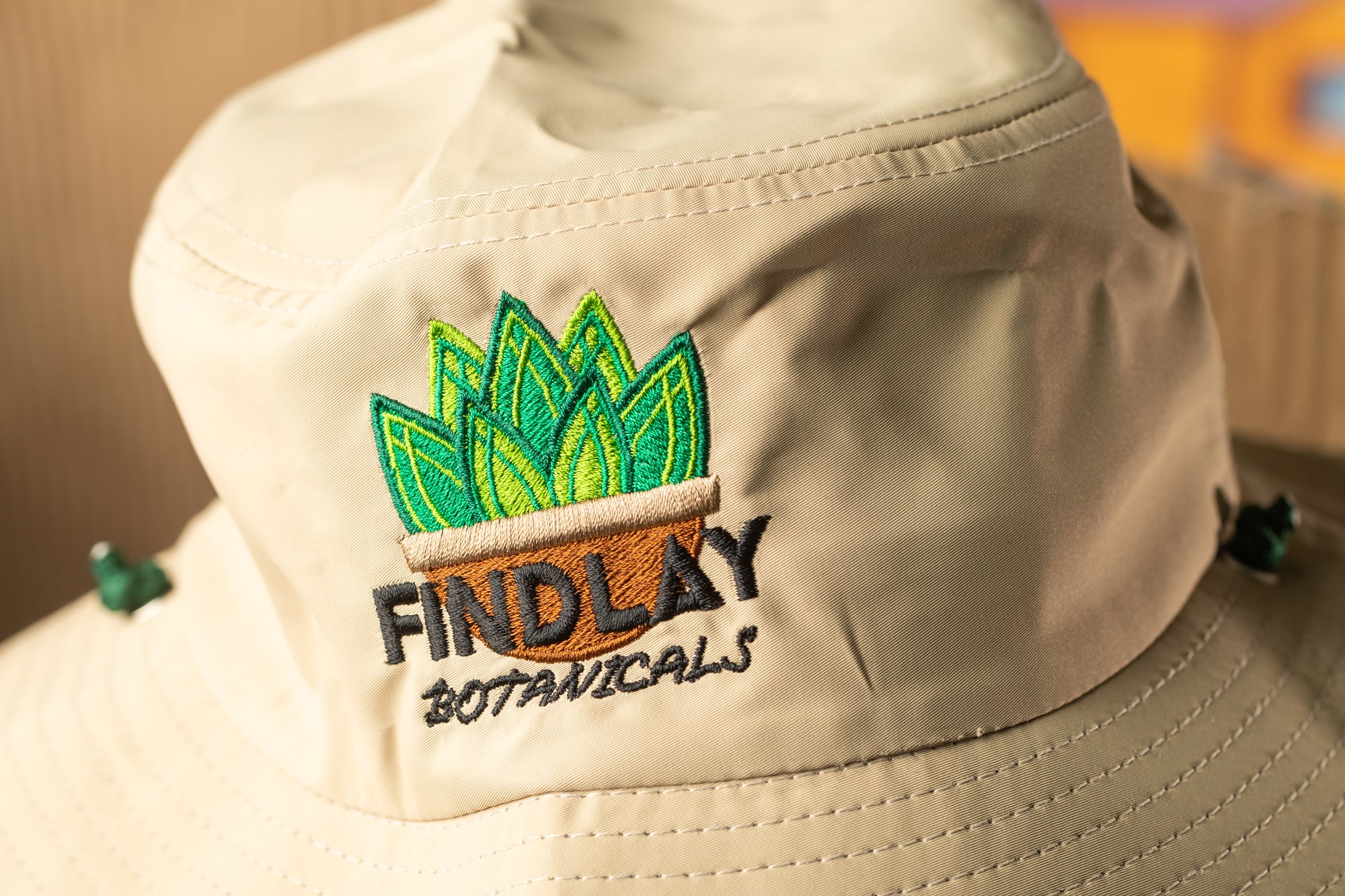 A beige bucket hat with a logo on the front.