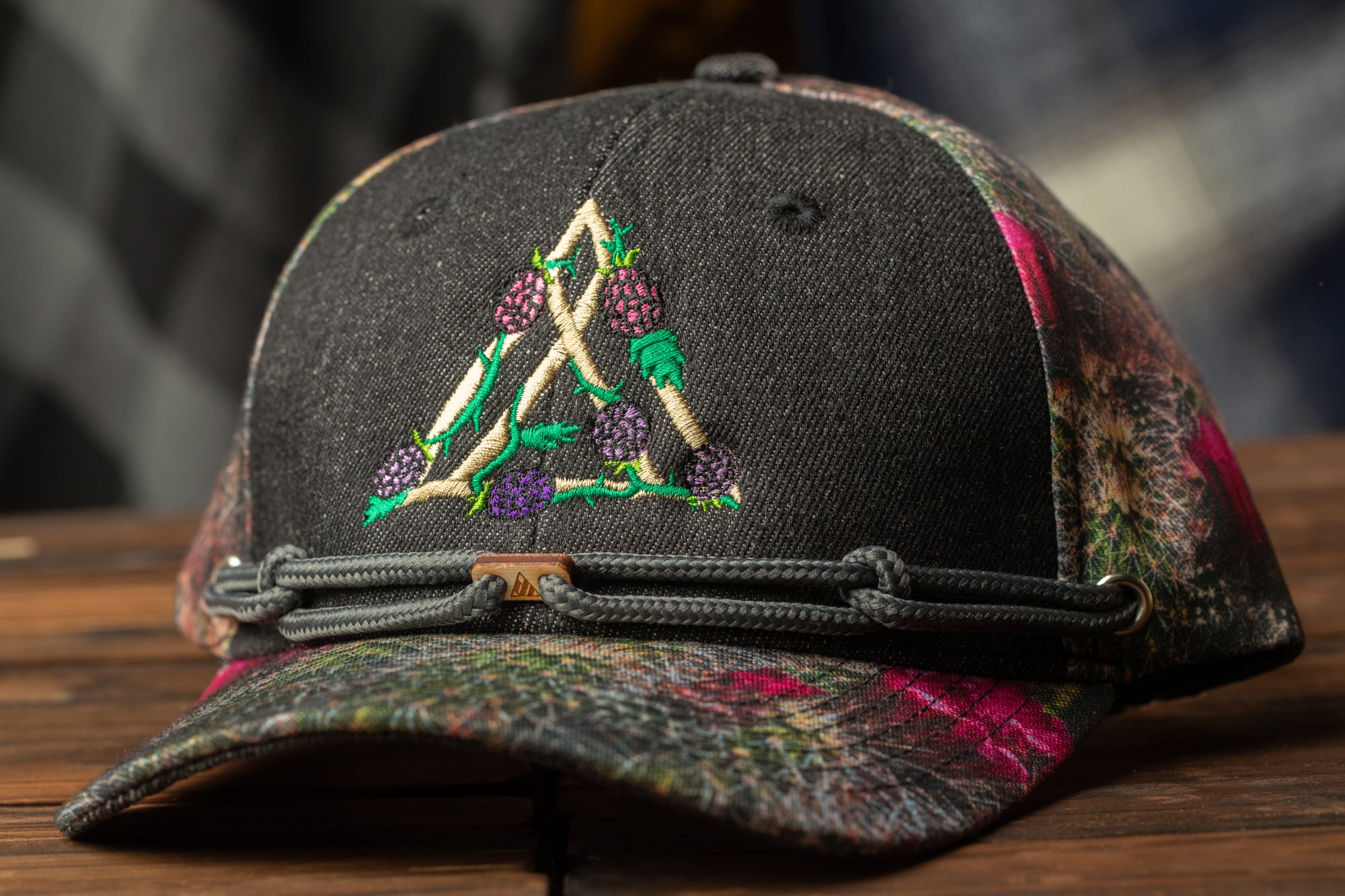 A black baseball cap with a floral pattern and a small triangle design on the front.