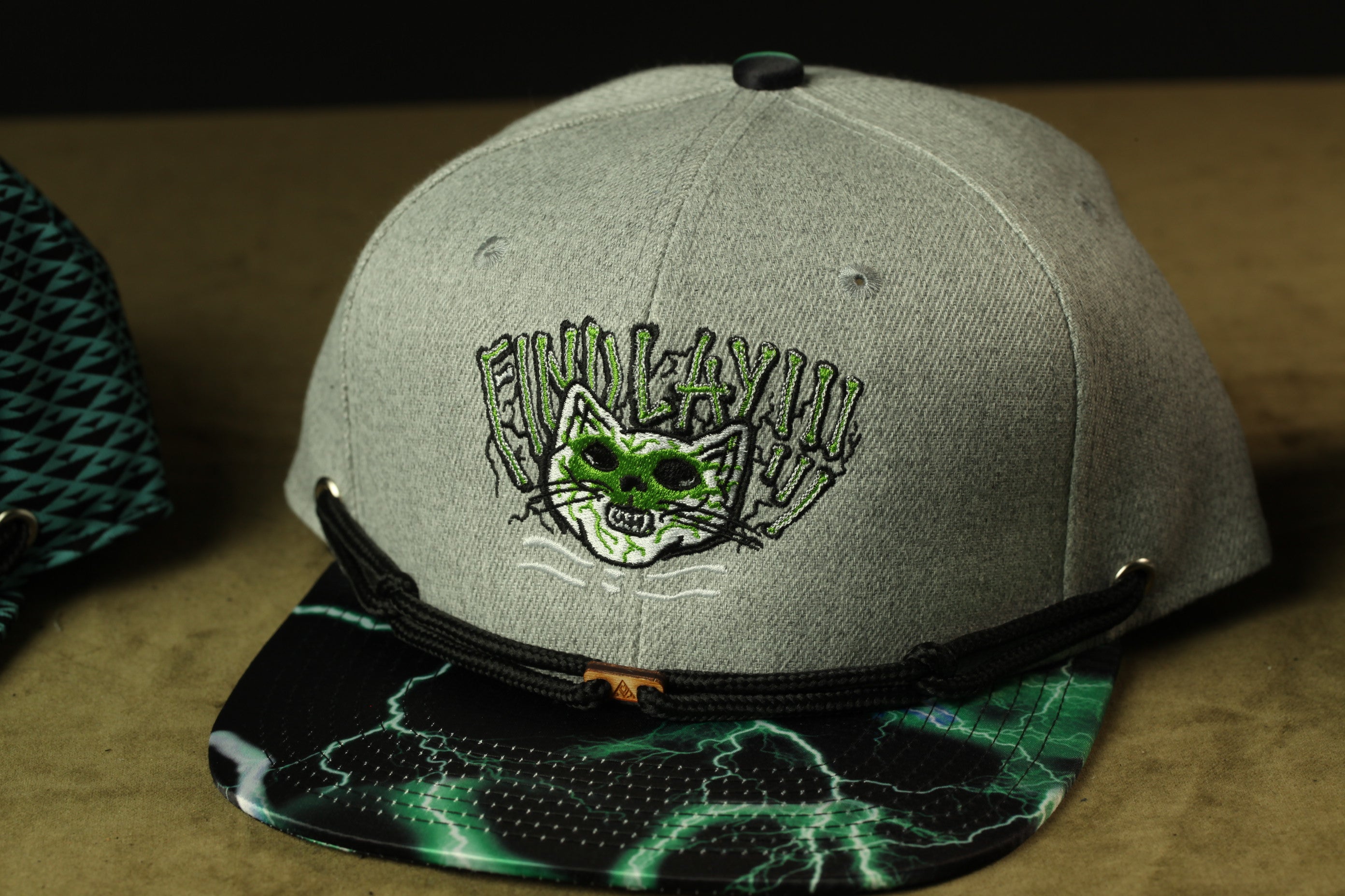 A gray baseball cap with a cat-like design and a lightning bolt pattern on the brim.