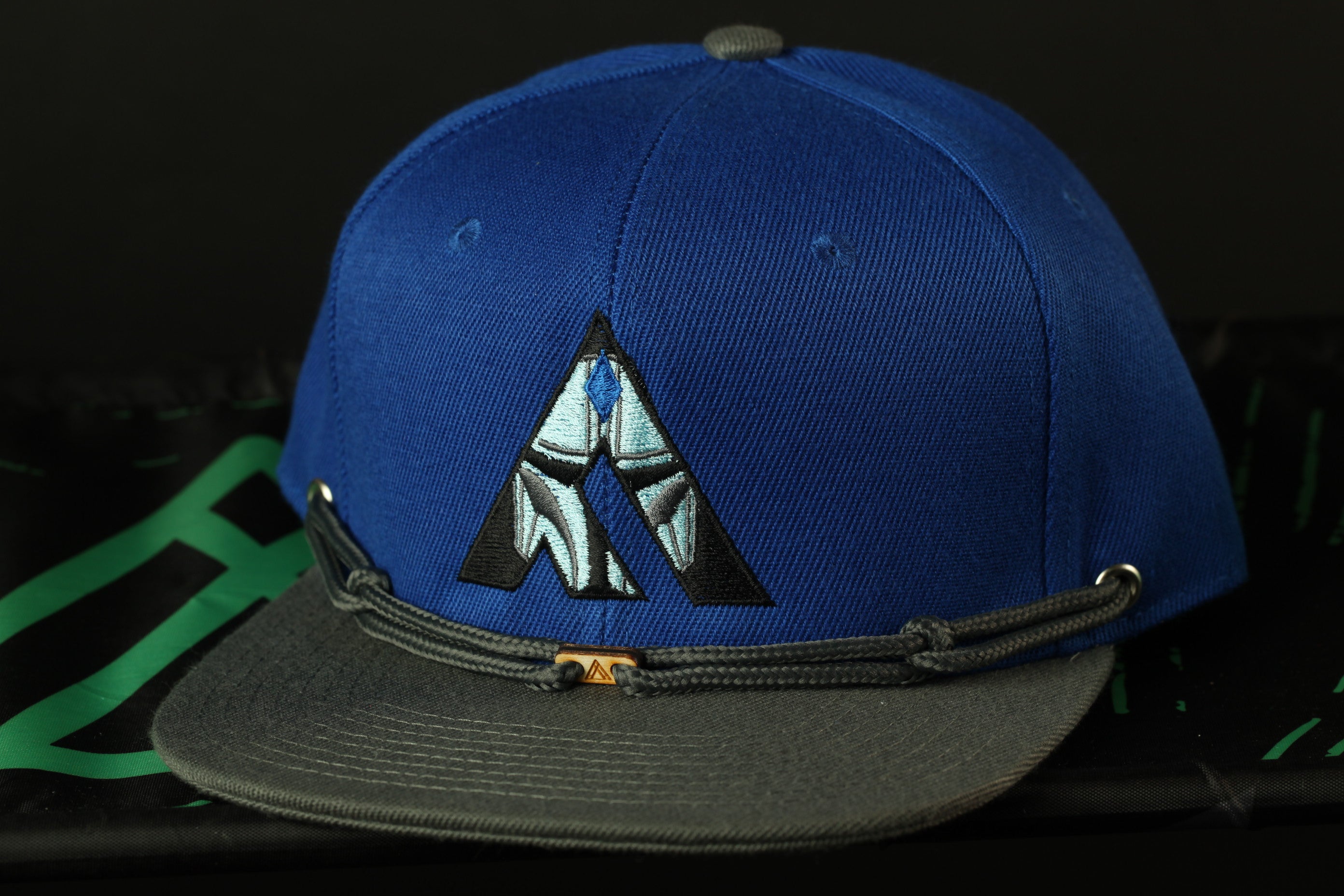 A blue baseball cap with a gray brim and a black and white logo on the front.