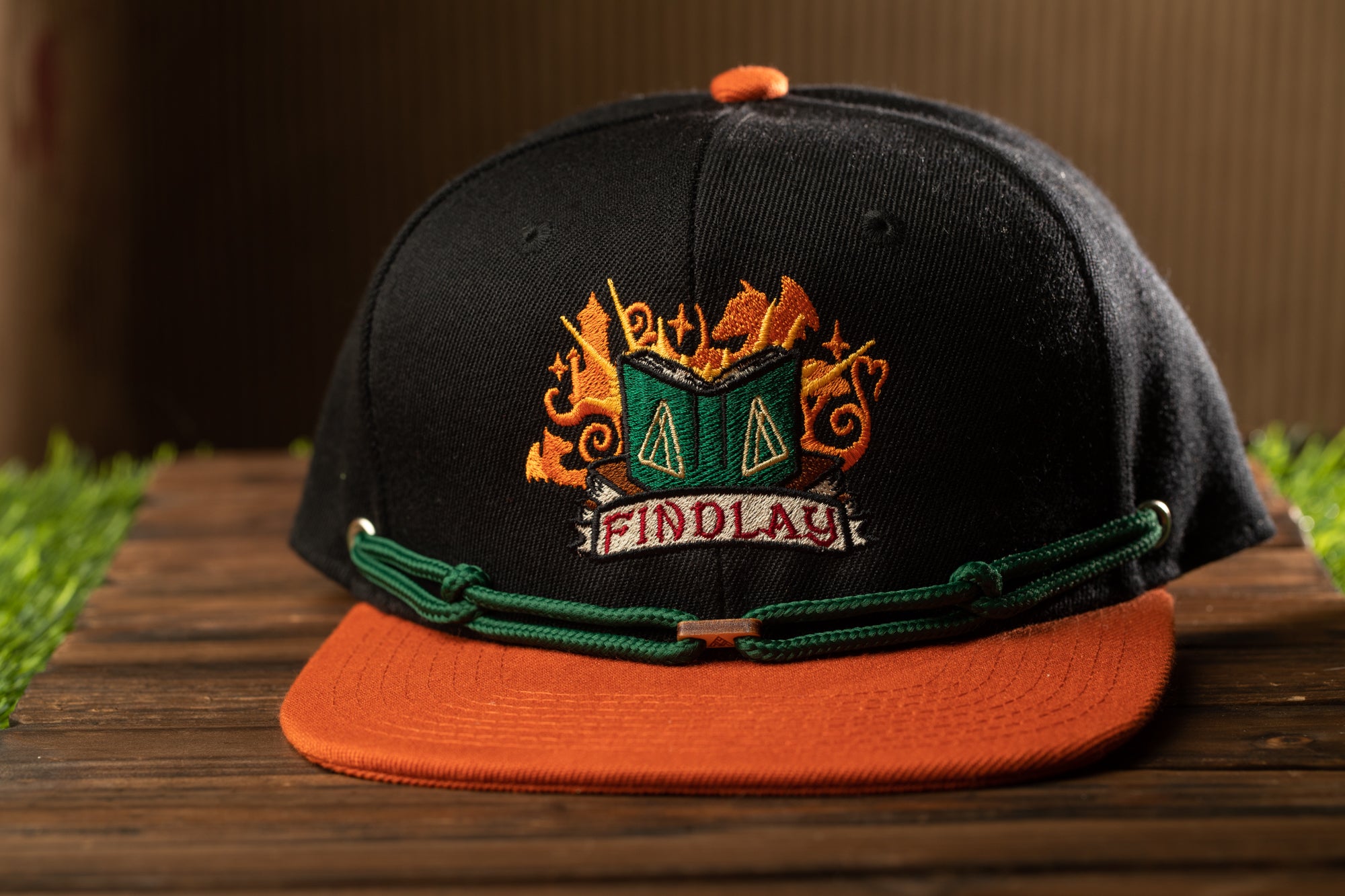 A black baseball cap with an orange brim and a green band, featuring an embroidered logo with the text "FINDOLAY" on the front.