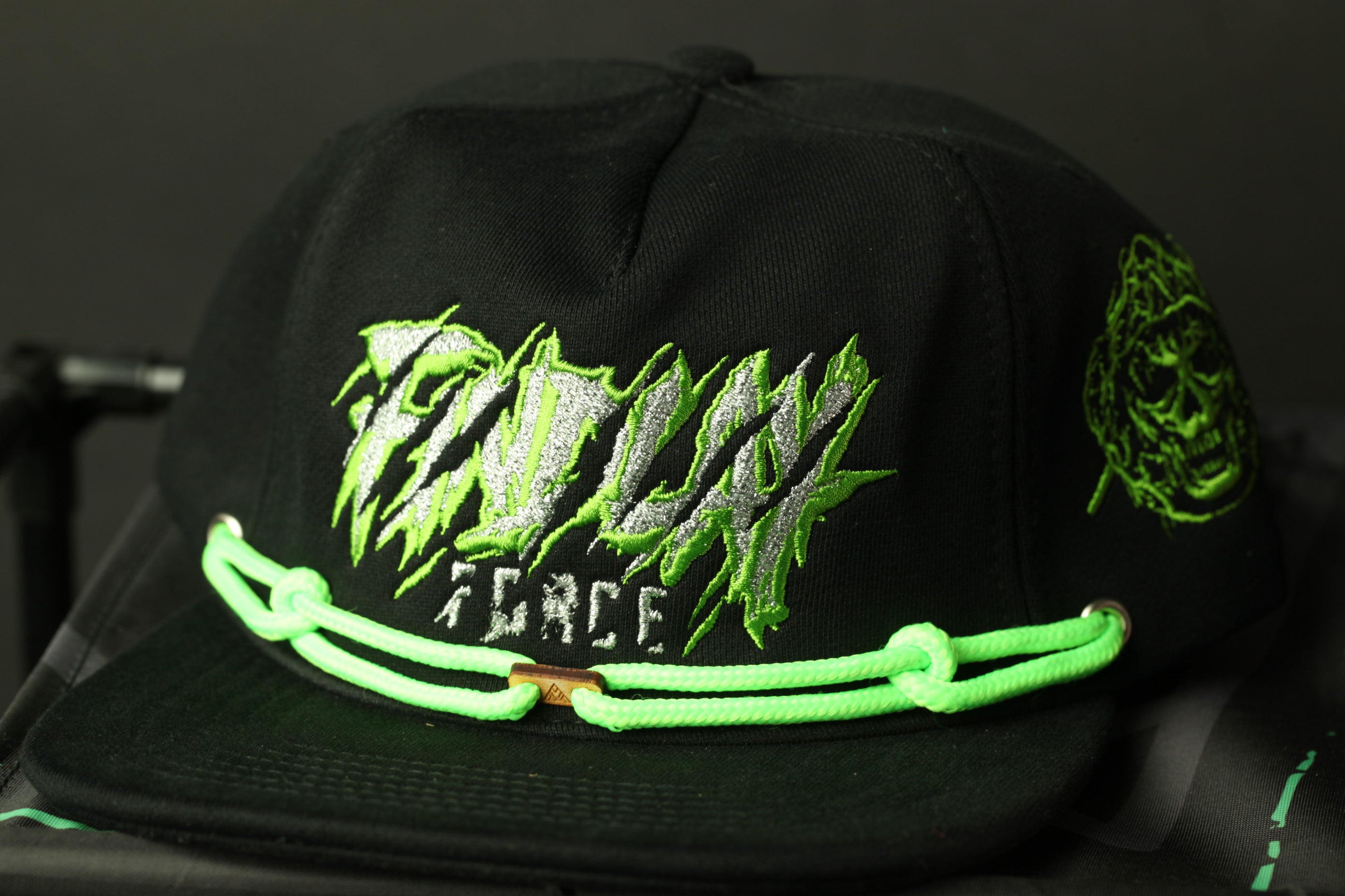 A black baseball cap with green and white text and graphics on it.