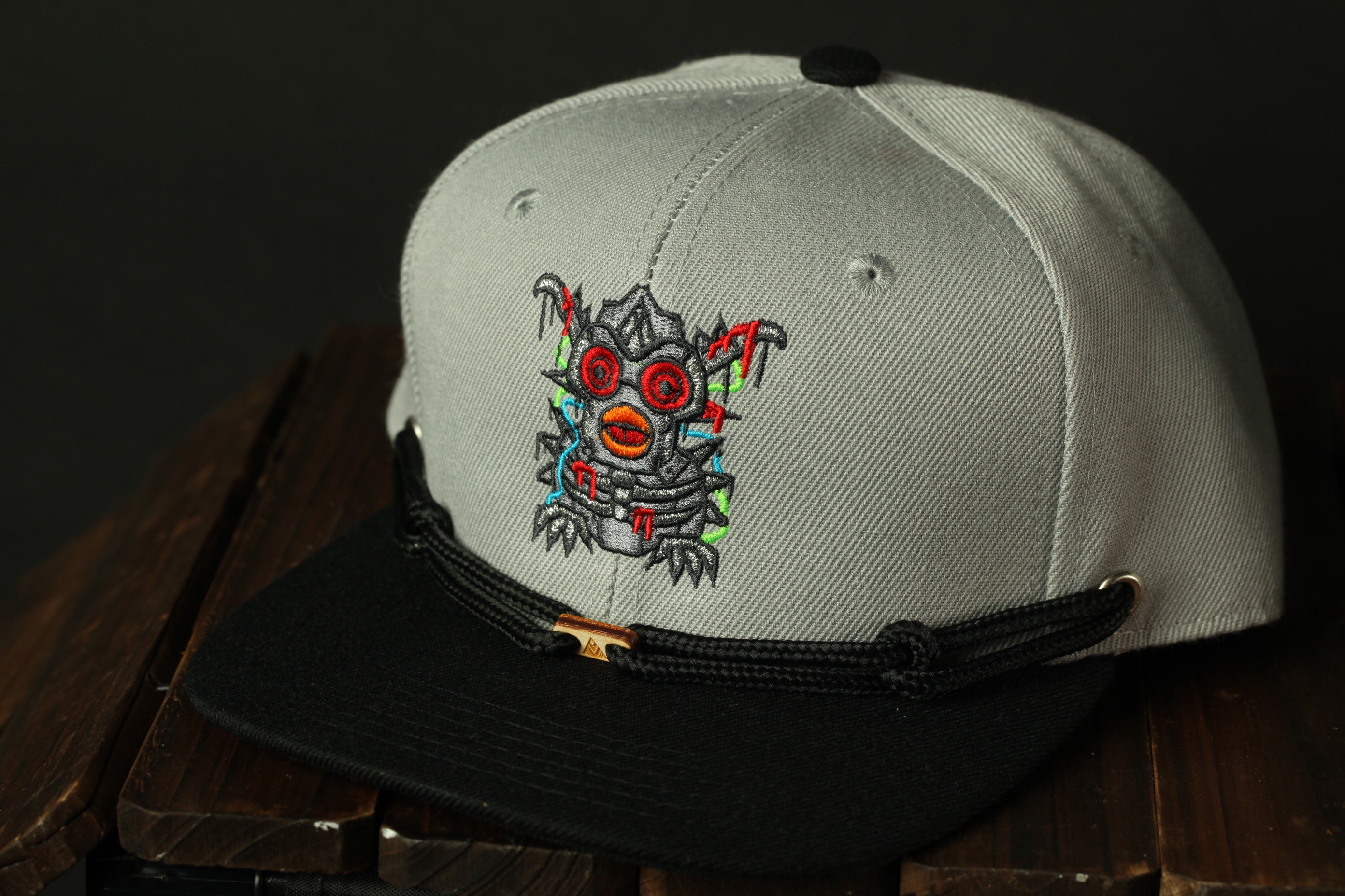 A gray baseball cap with a black brim and a colorful, abstract design on the front.
