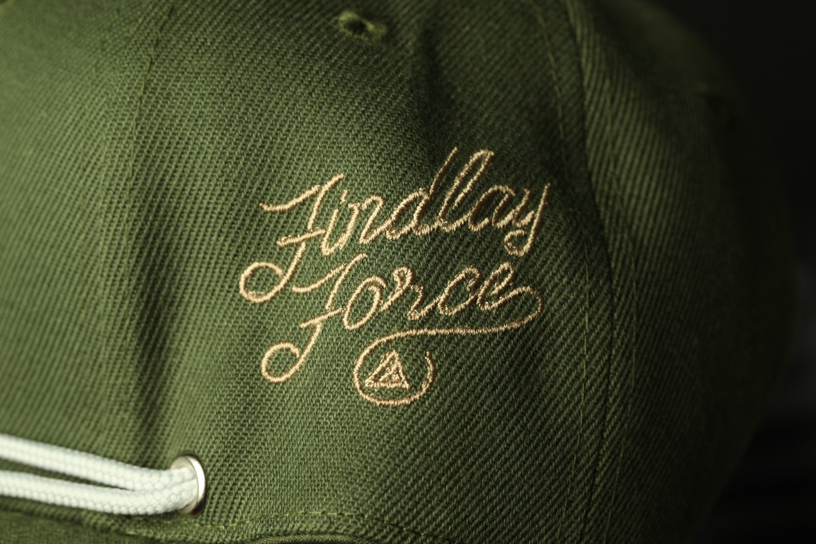 A close-up view of a green baseball cap with the embroidered text "Findlay Force" on it.