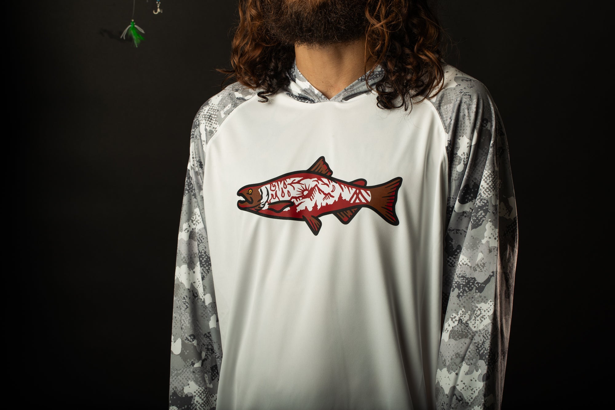 a man with long hair wearing a white shirt with a fish on it